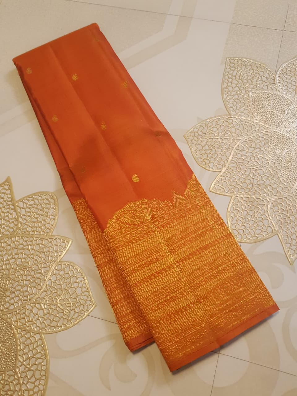 Burnt Orange Kanchipuram handloom pattu silk bridal saree featuring small gold buttas, intricate gold zari scalloped borders, and a certified silk mark weave.