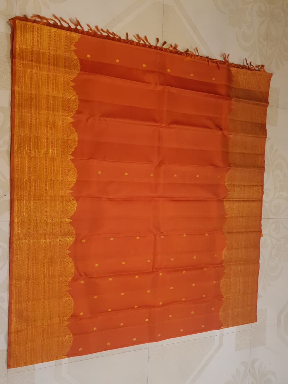 Burnt Orange Kanchipuram handloom pattu silk bridal saree featuring small gold buttas, intricate gold zari scalloped borders, and a certified silk mark weave.