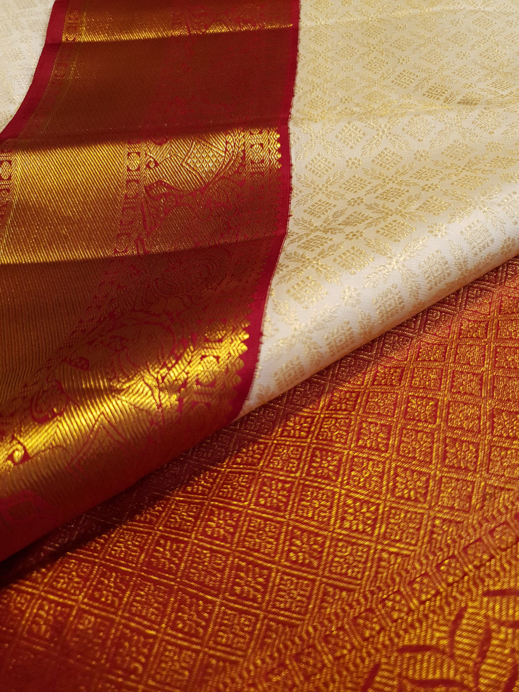 Off-white Kanchipuram handloom pattu silk bridal saree with a rich red and gold zari border.