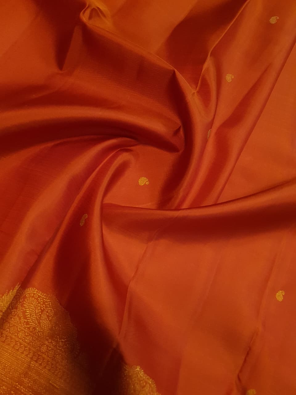 Burnt Orange Kanchipuram handloom pattu silk bridal saree featuring small gold buttas, intricate gold zari scalloped borders, and a certified silk mark weave.