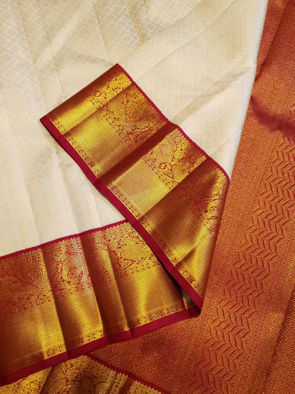 Off-white Kanchipuram handloom pattu silk bridal saree with a rich red and gold zari border.