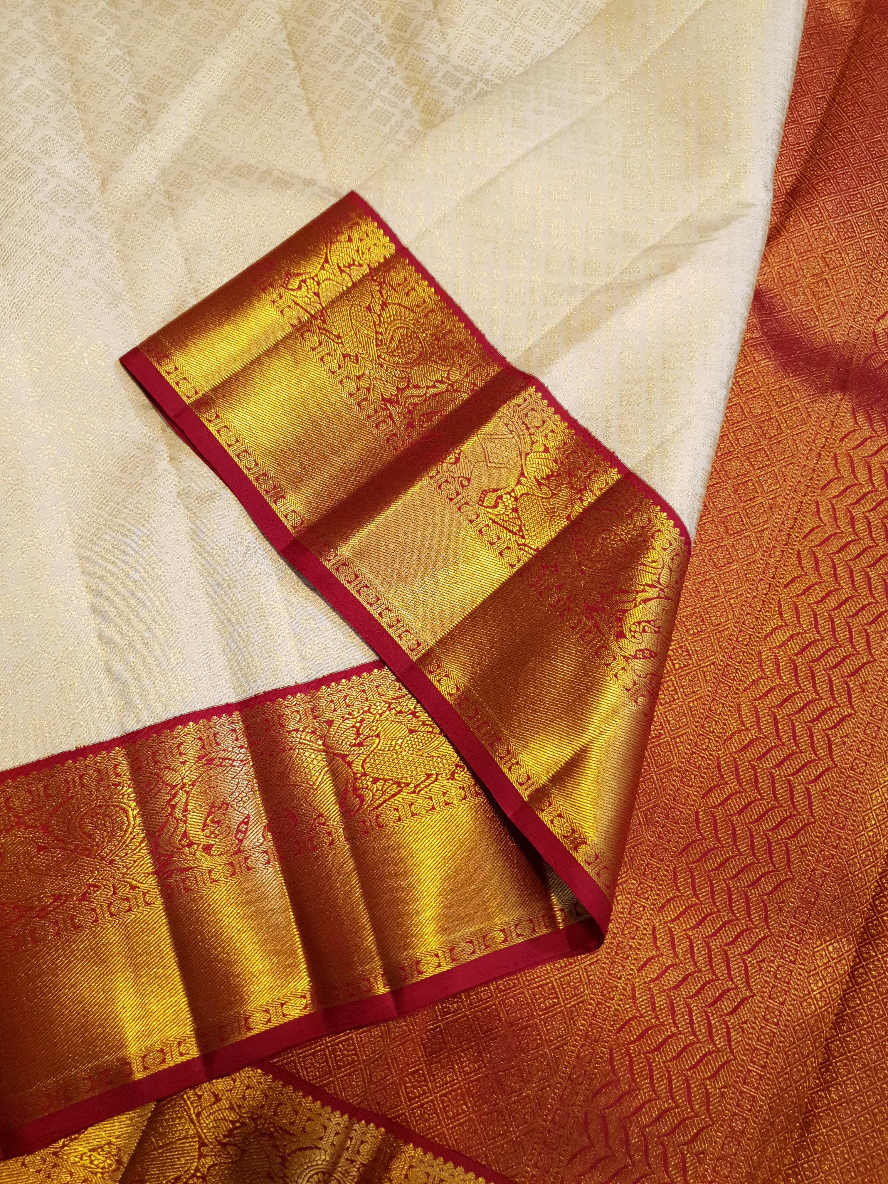 Off-white Kanchipuram handloom pattu silk bridal saree with a rich red and gold zari border.