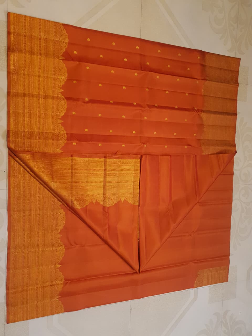 Burnt Orange Kanchipuram handloom pattu silk bridal saree featuring small gold buttas, intricate gold zari scalloped borders, and a certified silk mark weave.