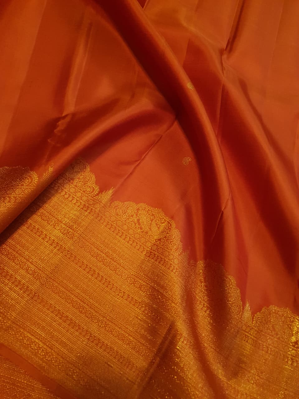 Burnt Orange Kanchipuram handloom pattu silk bridal saree featuring small gold buttas, intricate gold zari scalloped borders, and a certified silk mark weave.