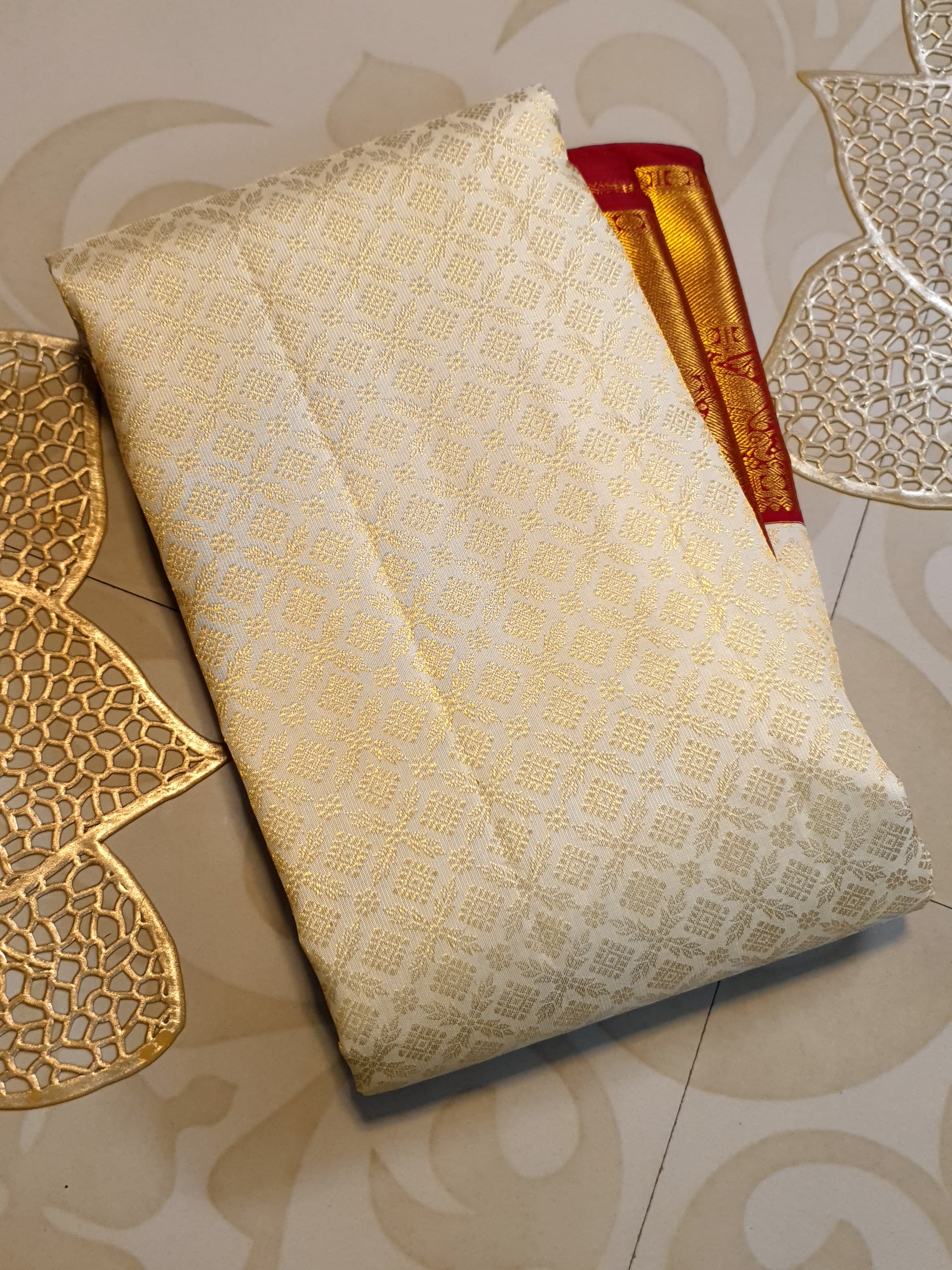 Off-white Kanchipuram handloom pattu silk bridal saree with a rich red and gold zari border.