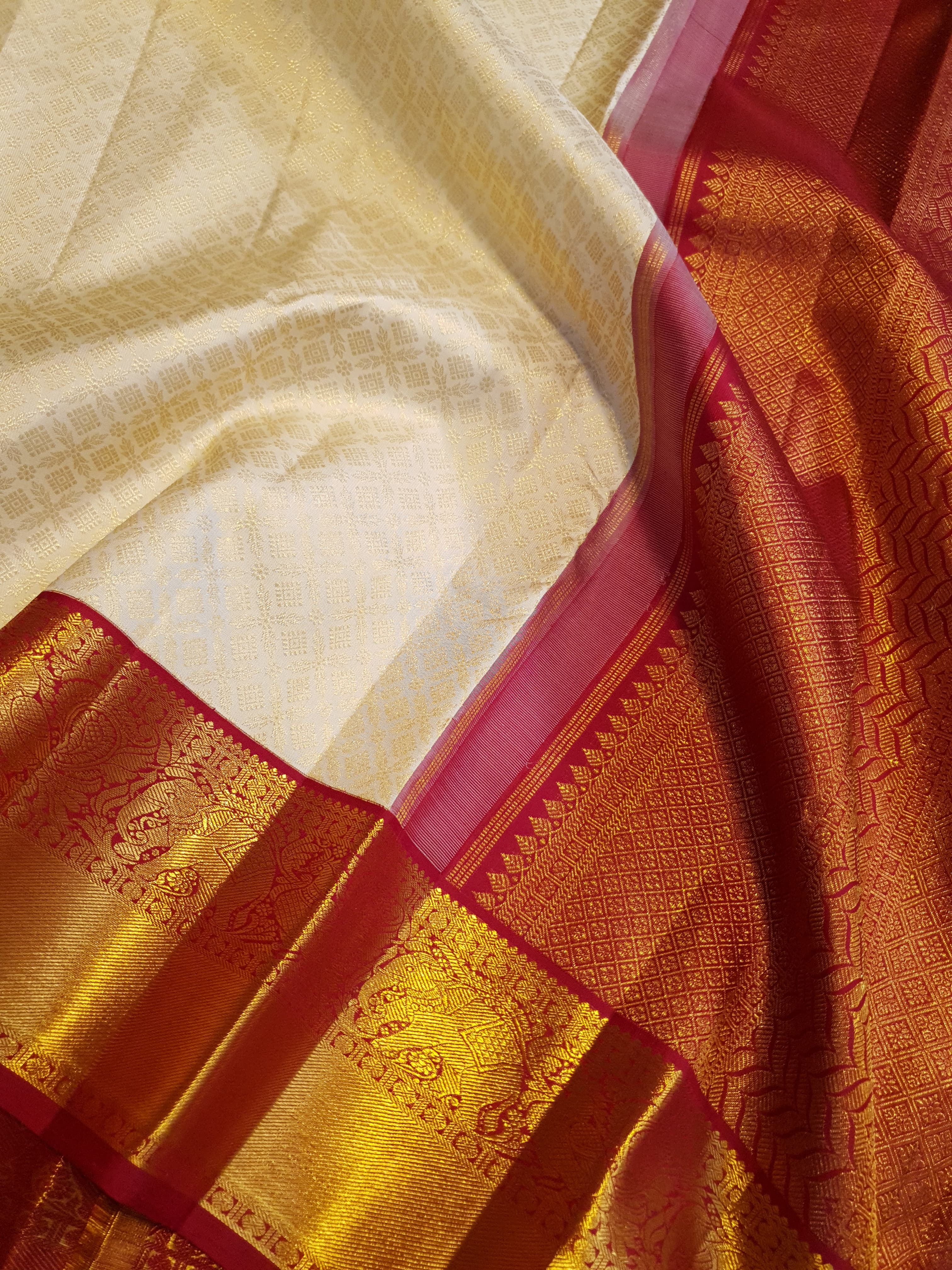 Off-white Kanchipuram handloom pattu silk bridal saree with a rich red and gold zari border.