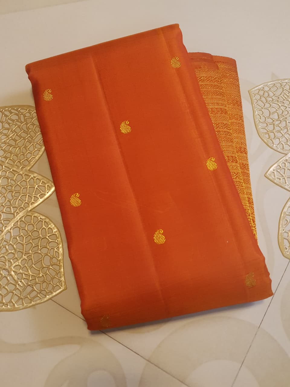 Burnt Orange Kanchipuram handloom pattu silk bridal saree featuring small gold buttas, intricate gold zari scalloped borders, and a certified silk mark weave.