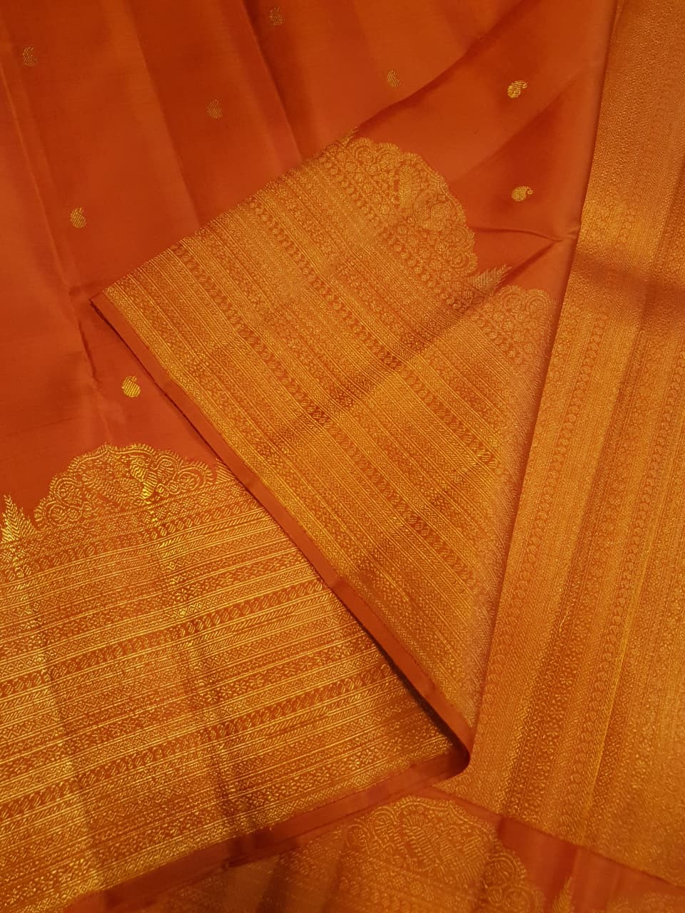 Burnt Orange Kanchipuram handloom pattu silk bridal saree featuring small gold buttas, intricate gold zari scalloped borders, and a certified silk mark weave.