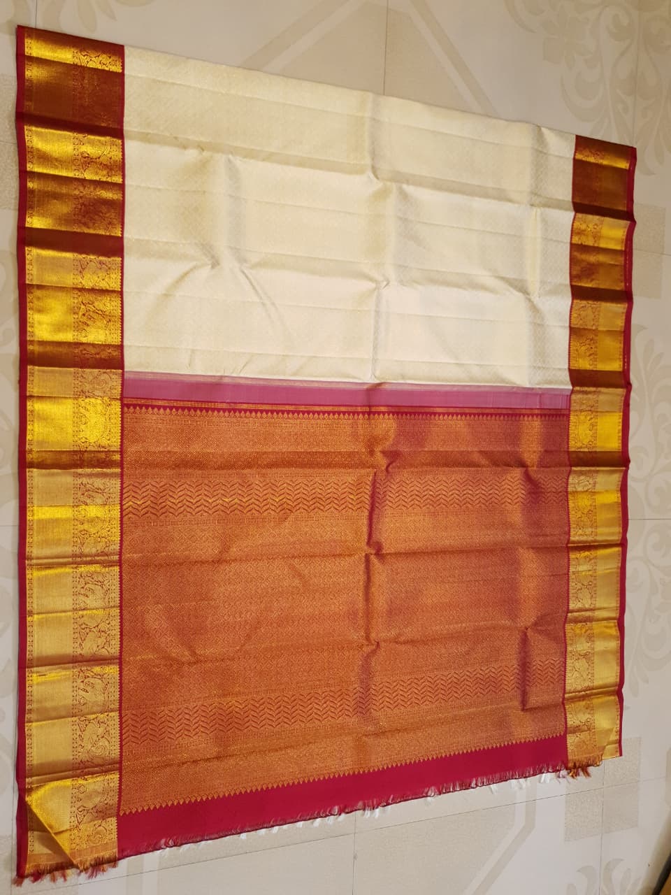 Off-white Kanchipuram handloom pattu silk bridal saree with a rich red and gold zari border.