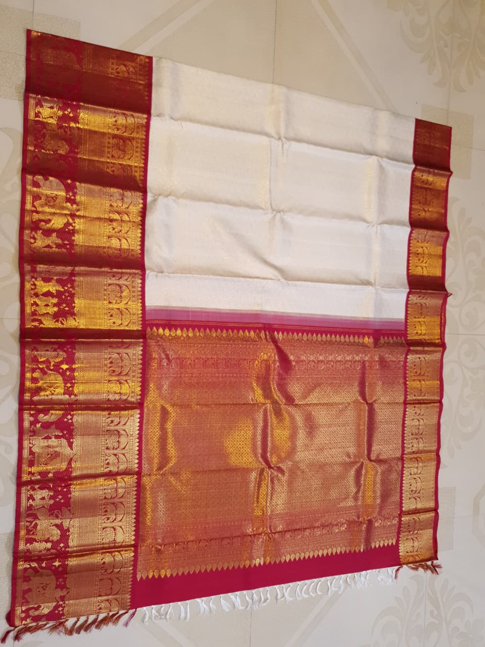 Cream Kanchipuram handloom silk saree with a vibrant pink and gold border, featuring intricate Kalyana Pallakku zari work, accessorized with traditional gold jewelry.