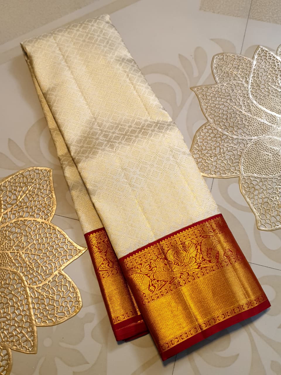 Off-white Kanchipuram handloom pattu silk bridal saree with a rich red and gold zari border.
