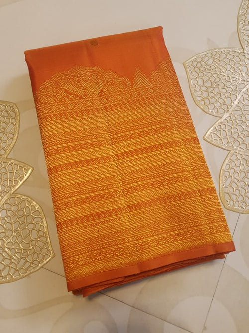 Burnt Orange Kanchipuram handloom pattu silk bridal saree featuring small gold buttas, intricate gold zari scalloped borders, and a certified silk mark weave.