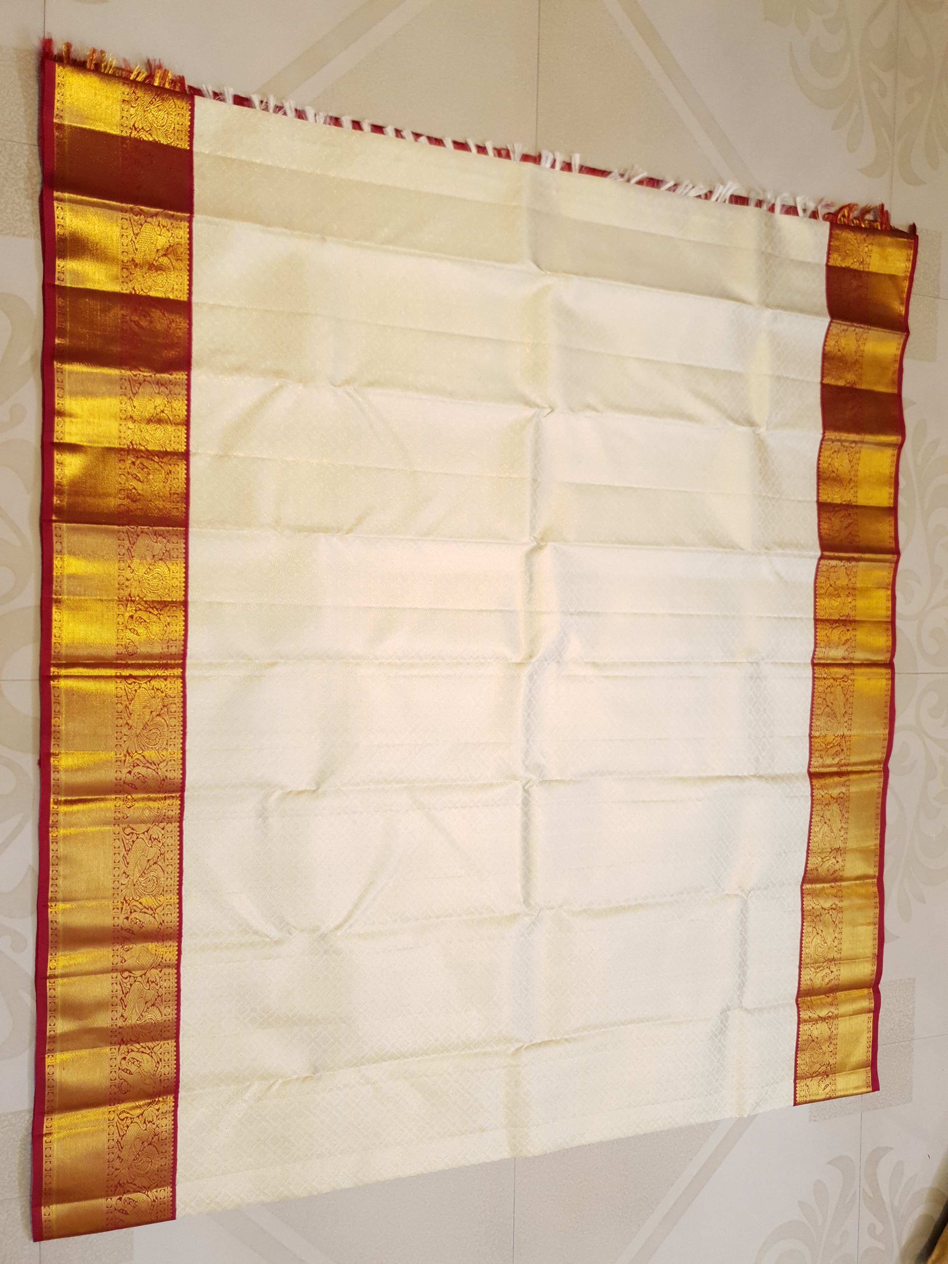 Off-white Kanchipuram handloom pattu silk bridal saree with a rich red and gold zari border.
