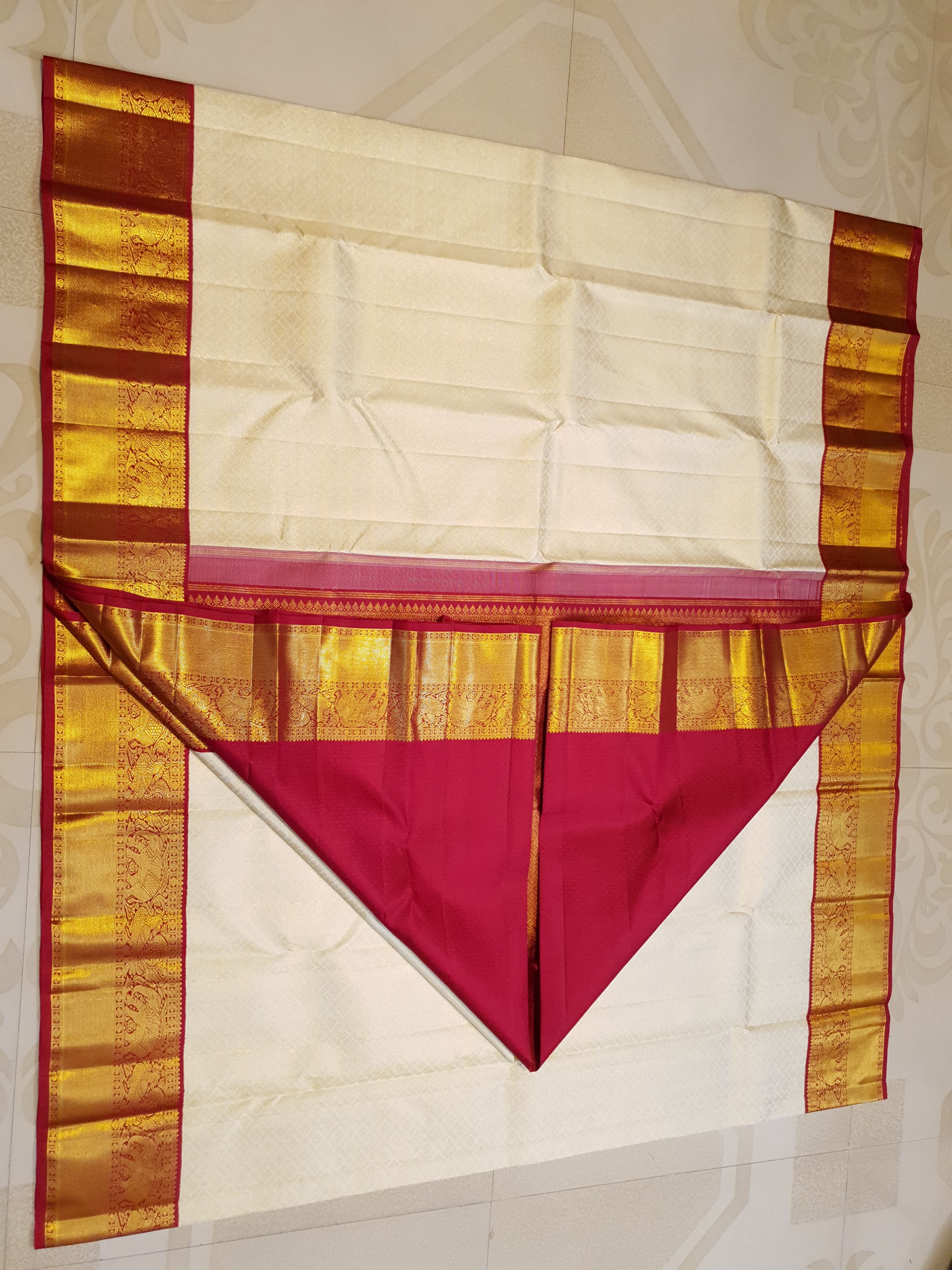 Off-white Kanchipuram handloom pattu silk bridal saree with a rich red and gold zari border.