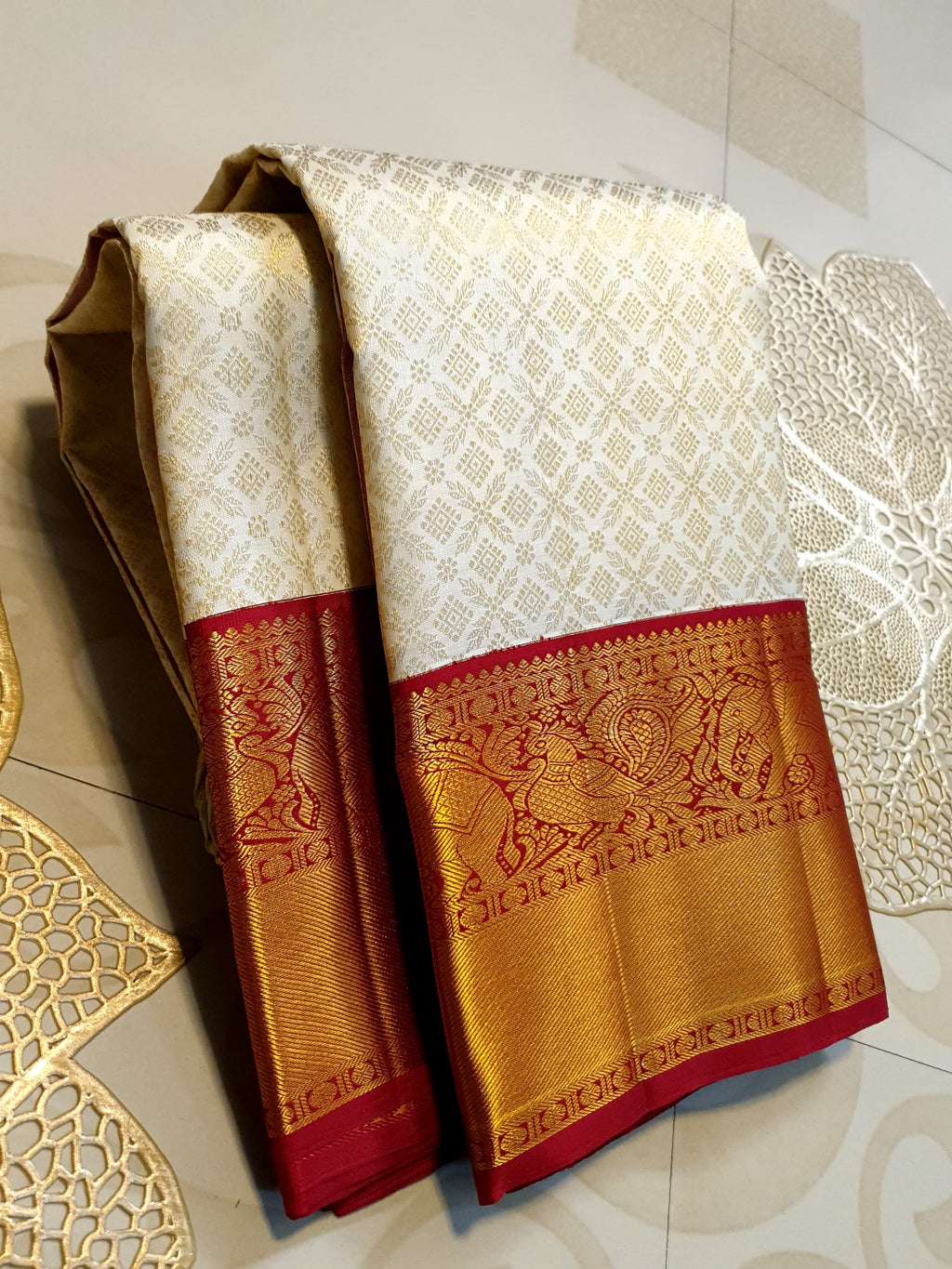 Off-white Kanchipuram handloom pattu silk bridal saree with a rich red and gold zari border.