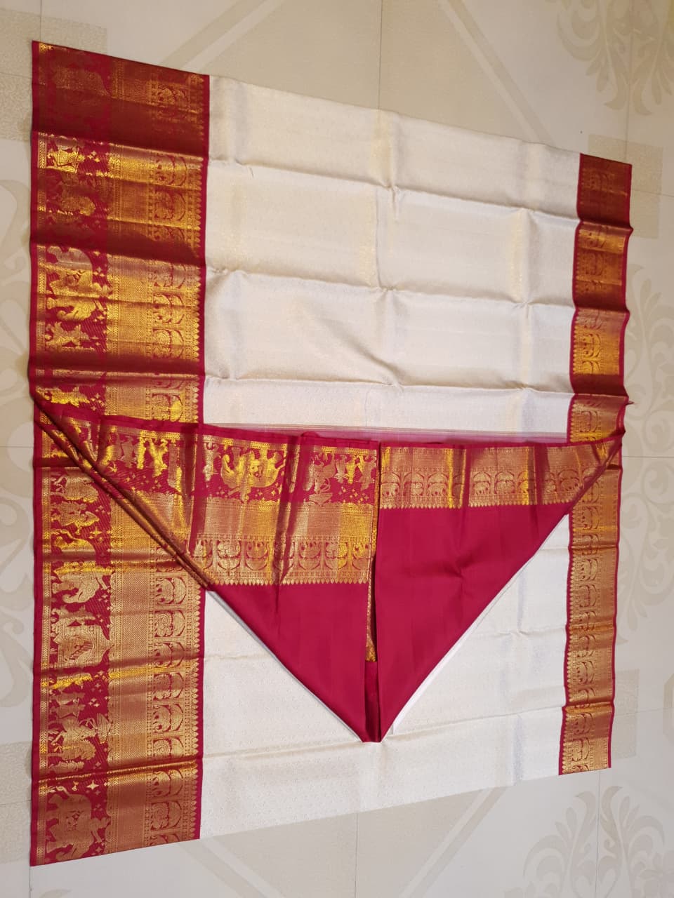 Cream Kanchipuram handloom silk saree with a vibrant pink and gold border, featuring intricate Kalyana Pallakku zari work, accessorized with traditional gold jewelry.