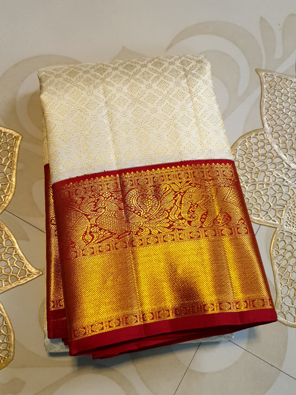 Off-white Kanchipuram handloom pattu silk bridal saree with a rich red and gold zari border.