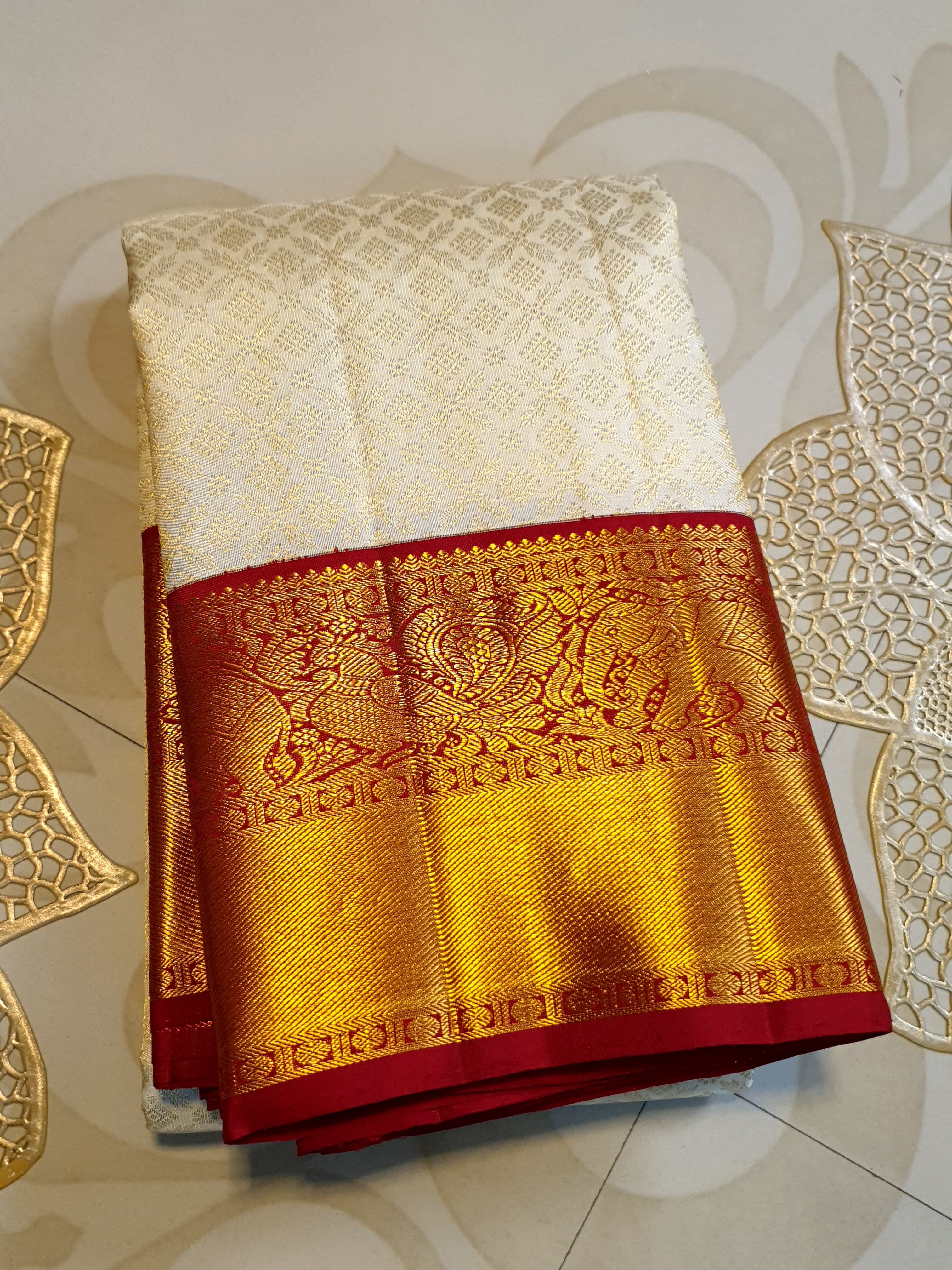 Off-white Kanchipuram handloom pattu silk bridal saree with a rich red and gold zari border.