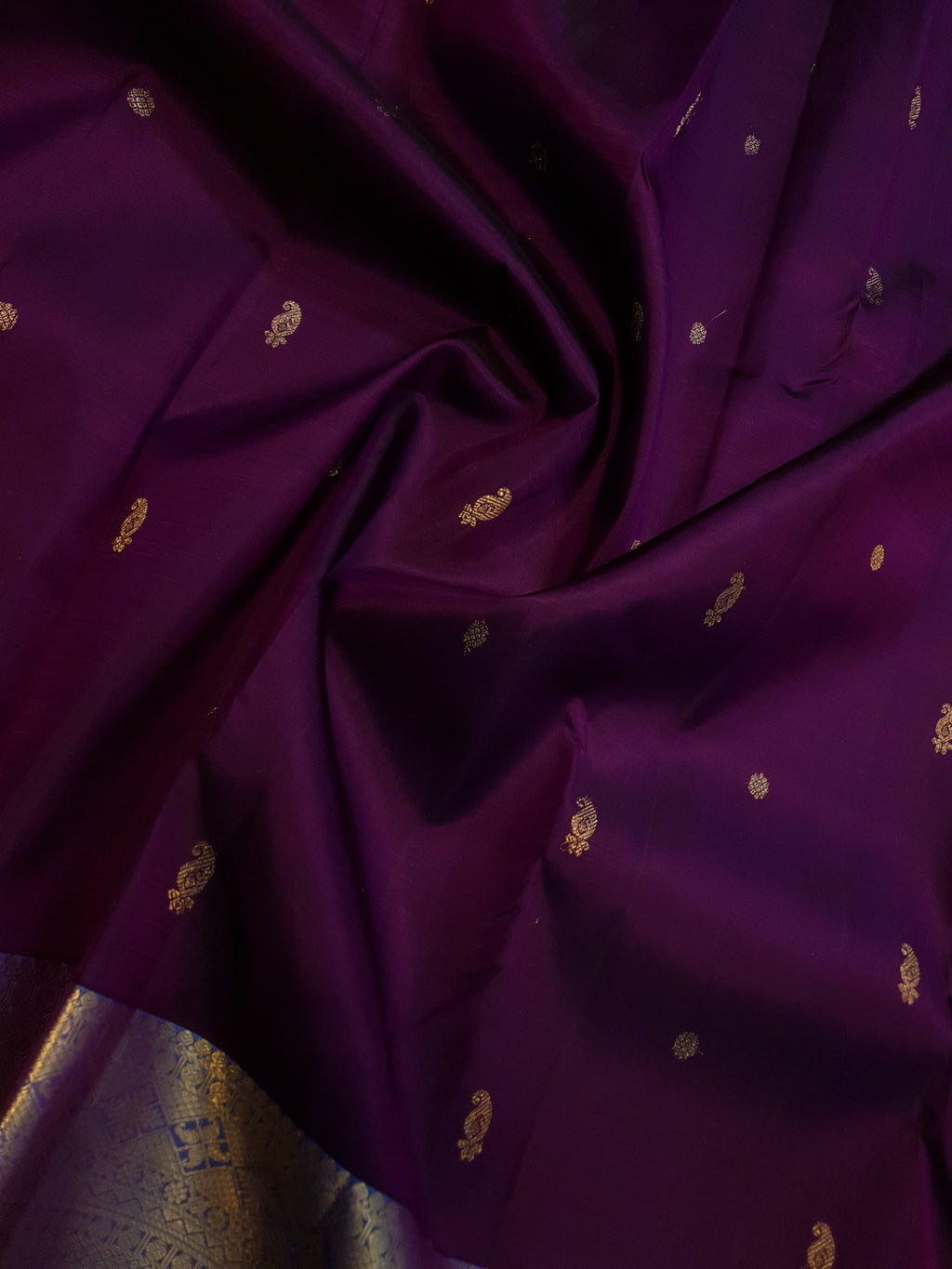 Dark plum Kanchipuram silk saree featuring a gold zari buttas, and a vibrant contrast border and pallu.