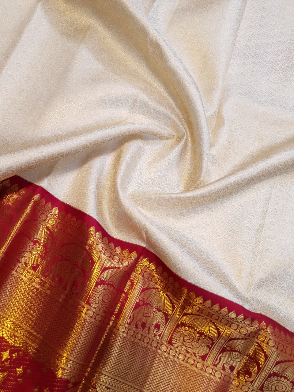 Cream Kanchipuram handloom silk saree with a vibrant pink and gold border, featuring intricate Kalyana Pallakku zari work, accessorized with traditional gold jewelry.