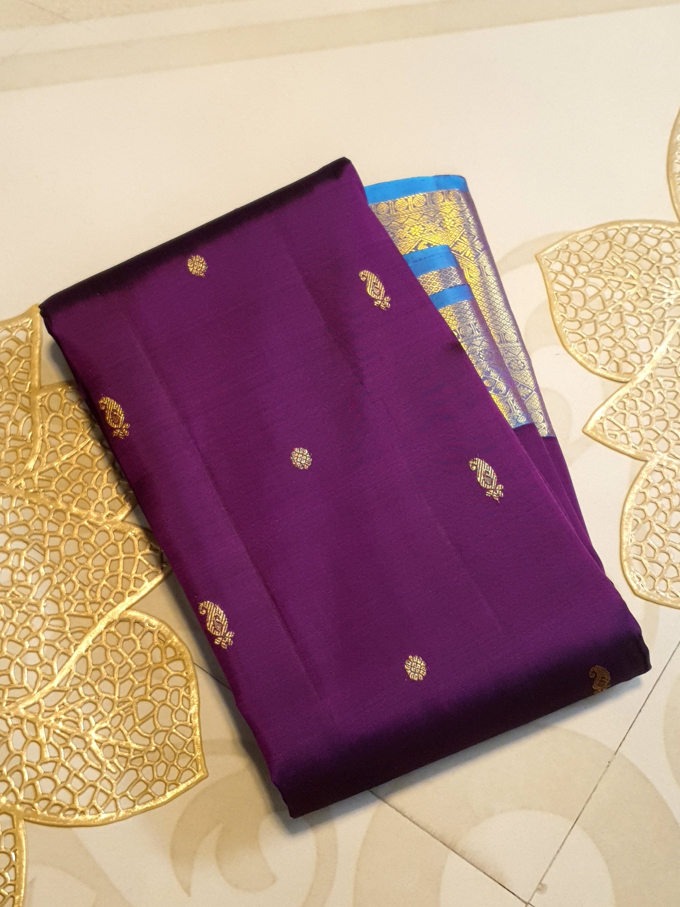 Dark plum Kanchipuram silk saree featuring a gold zari buttas, and a vibrant contrast border and pallu.