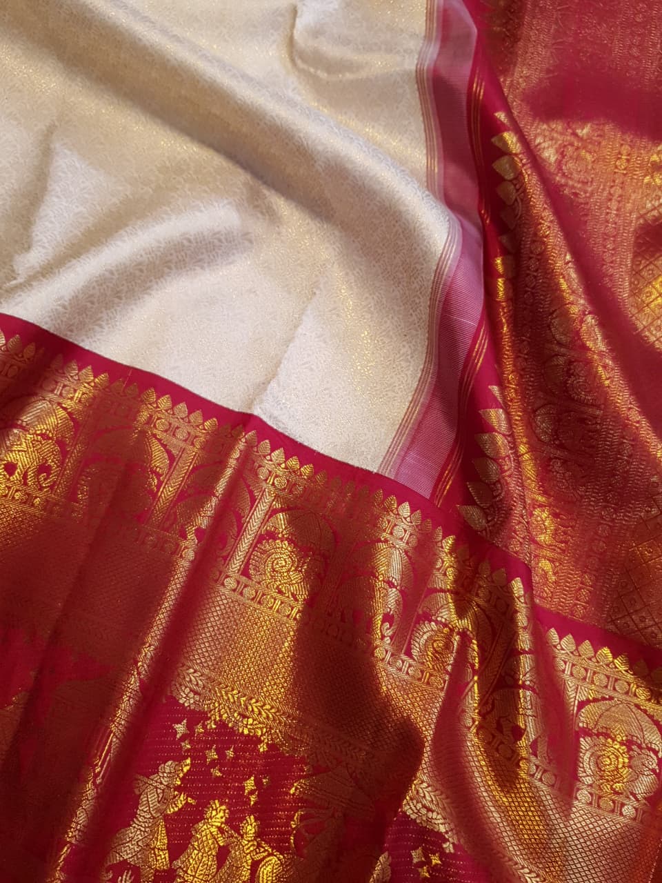 Cream Kanchipuram handloom silk saree with a vibrant pink and gold border, featuring intricate Kalyana Pallakku zari work, accessorized with traditional gold jewelry.