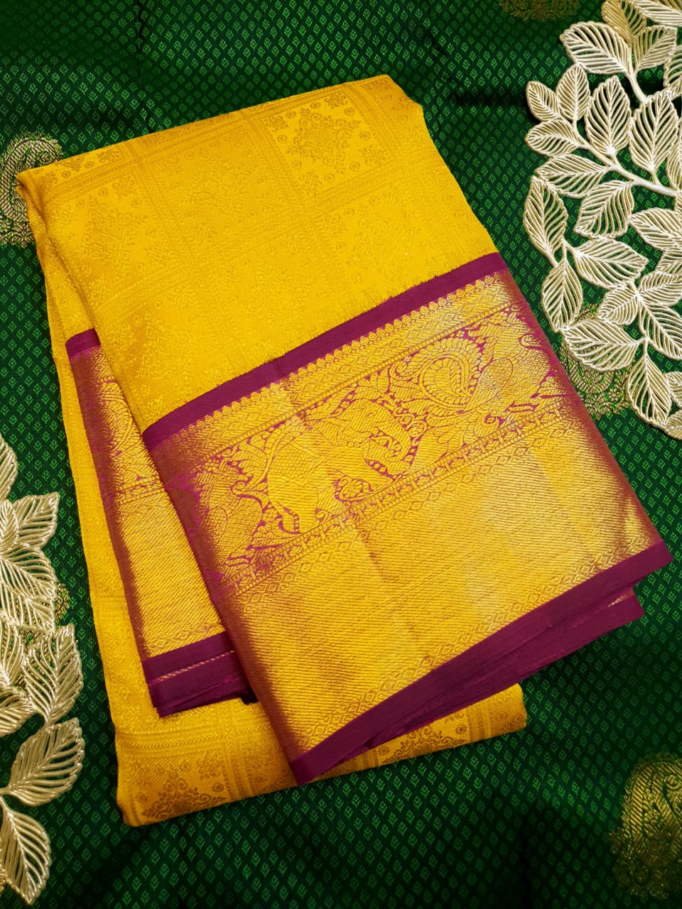 Traditional golden yellow Kanchipuram handloom 2G gold pattu silk saree with a rich magenta and zari woven border in a festive setting.