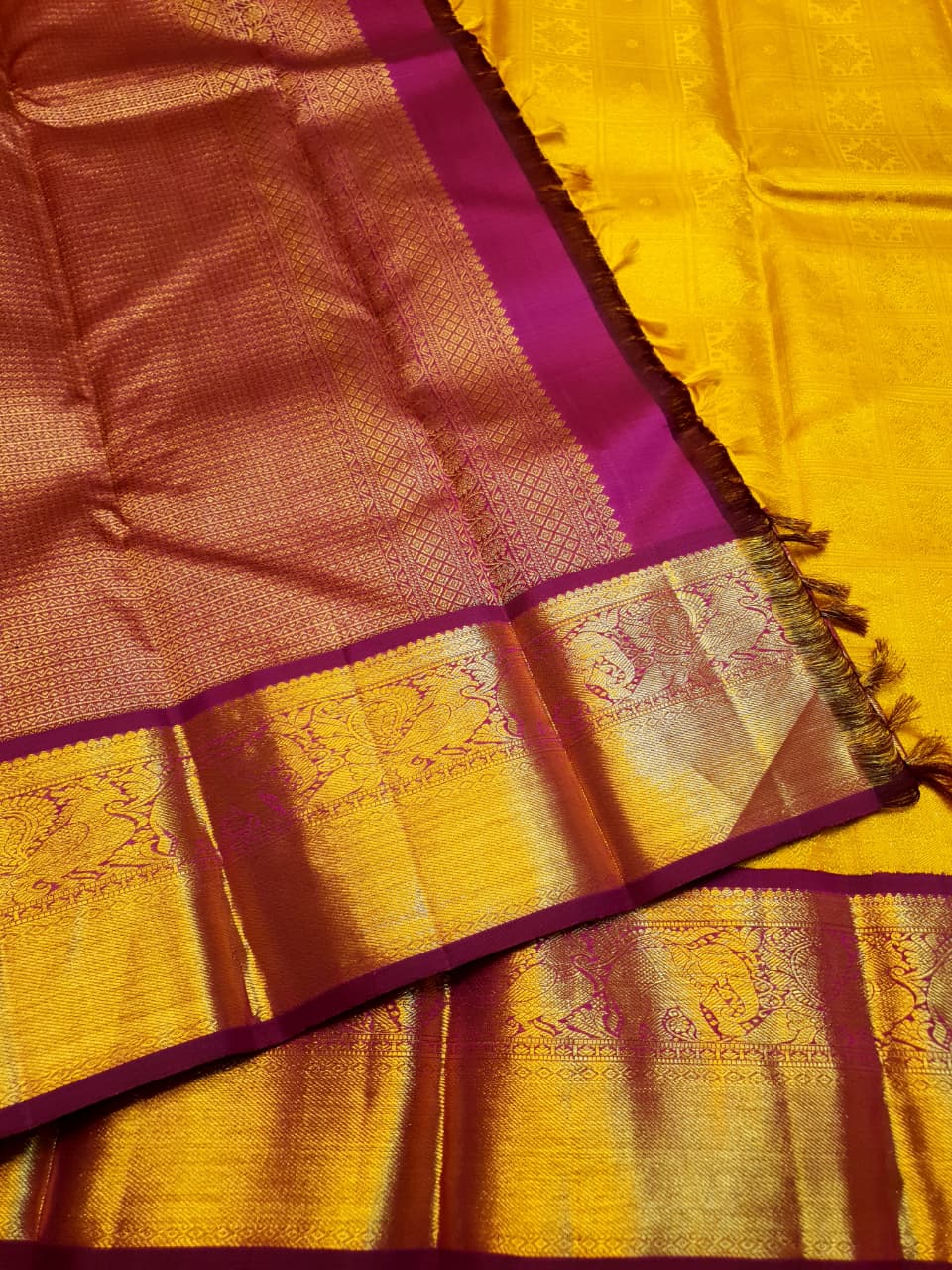 Traditional golden yellow Kanchipuram handloom 2G gold pattu silk saree with a rich magenta and zari woven border in a festive setting.