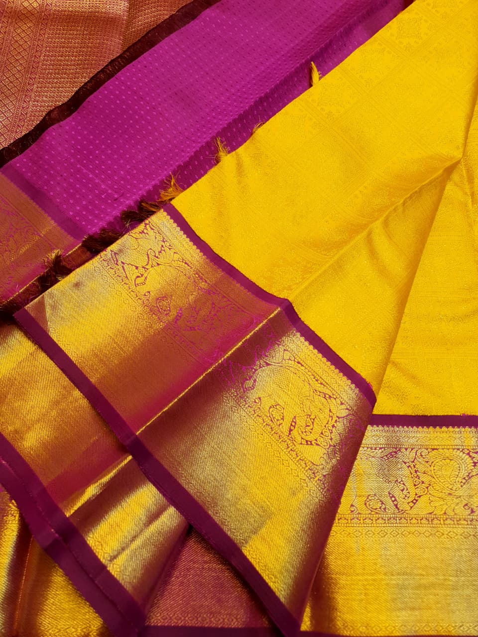 Traditional golden yellow Kanchipuram handloom 2G gold pattu silk saree with a rich magenta and zari woven border in a festive setting.