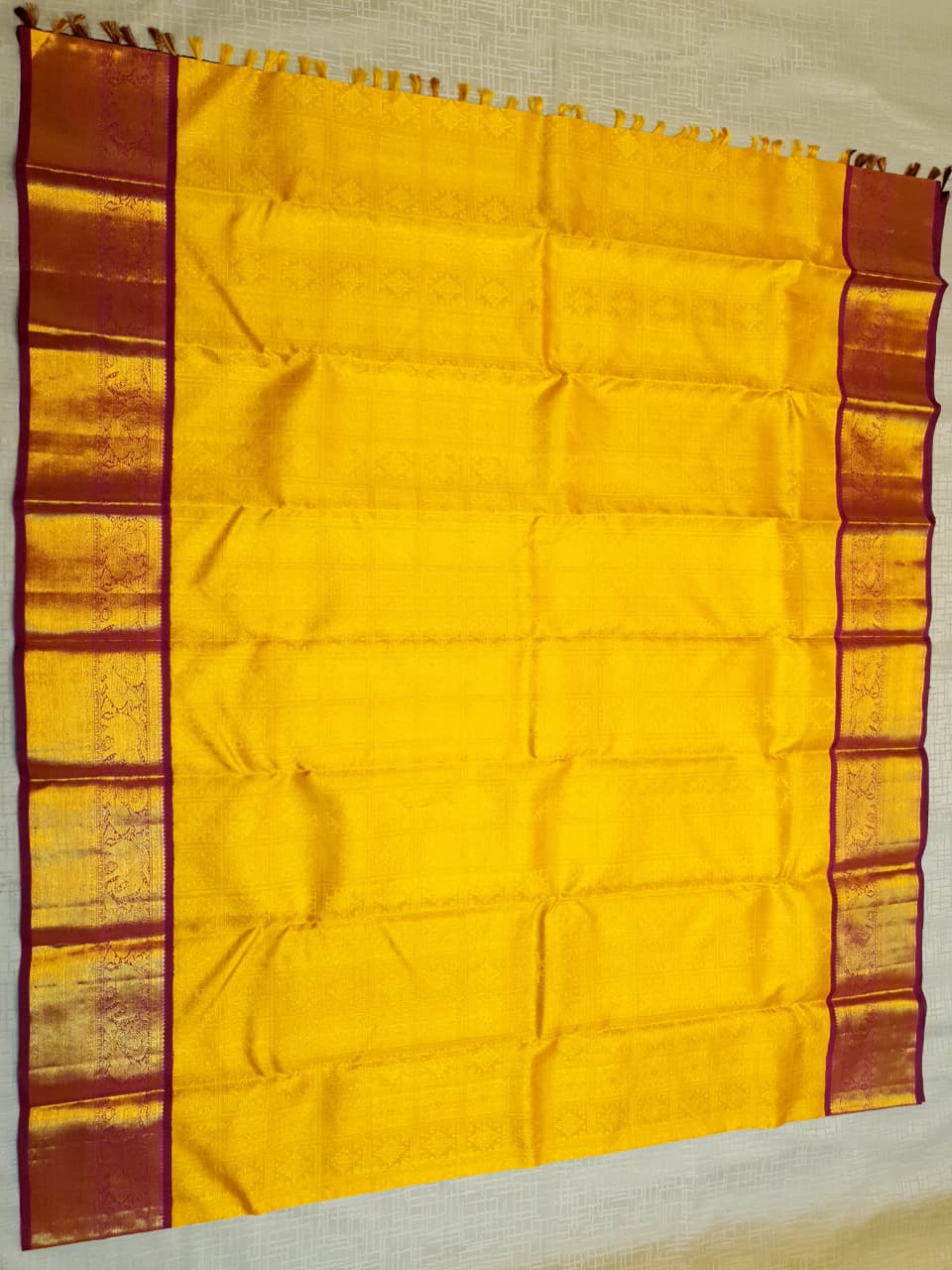 Traditional golden yellow Kanchipuram handloom 2G gold pattu silk saree with a rich magenta and zari woven border in a festive setting.