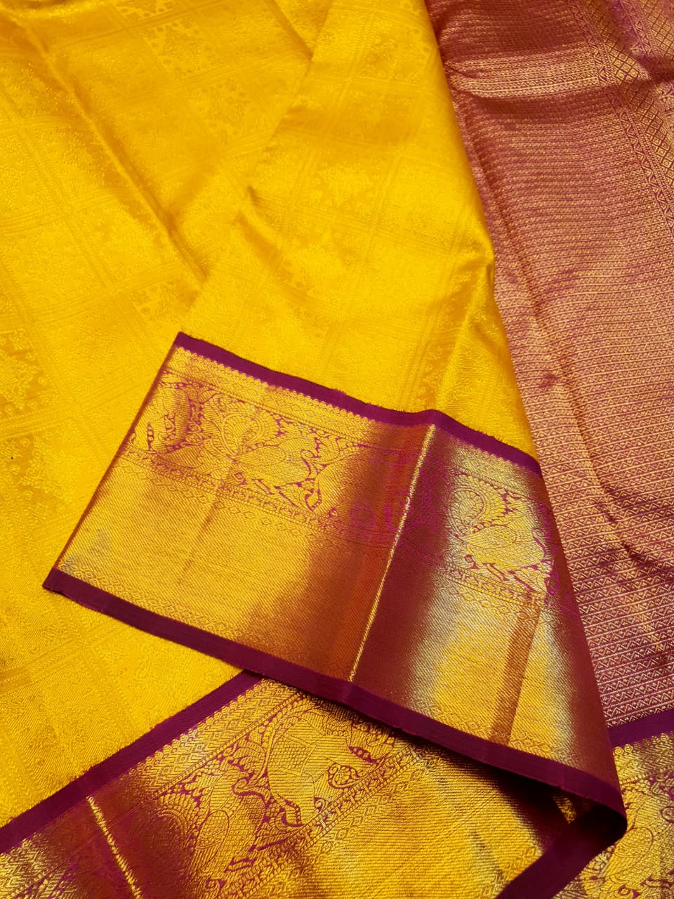 Traditional golden yellow Kanchipuram handloom 2G gold pattu silk saree with a rich magenta and zari woven border in a festive setting.