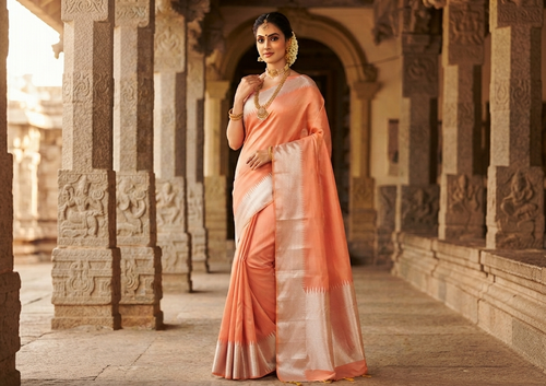 A model elegantly draped in a coral Kanchipuram handloom silk saree featuring a detailed silver zari temple border and luxurious silver accents.