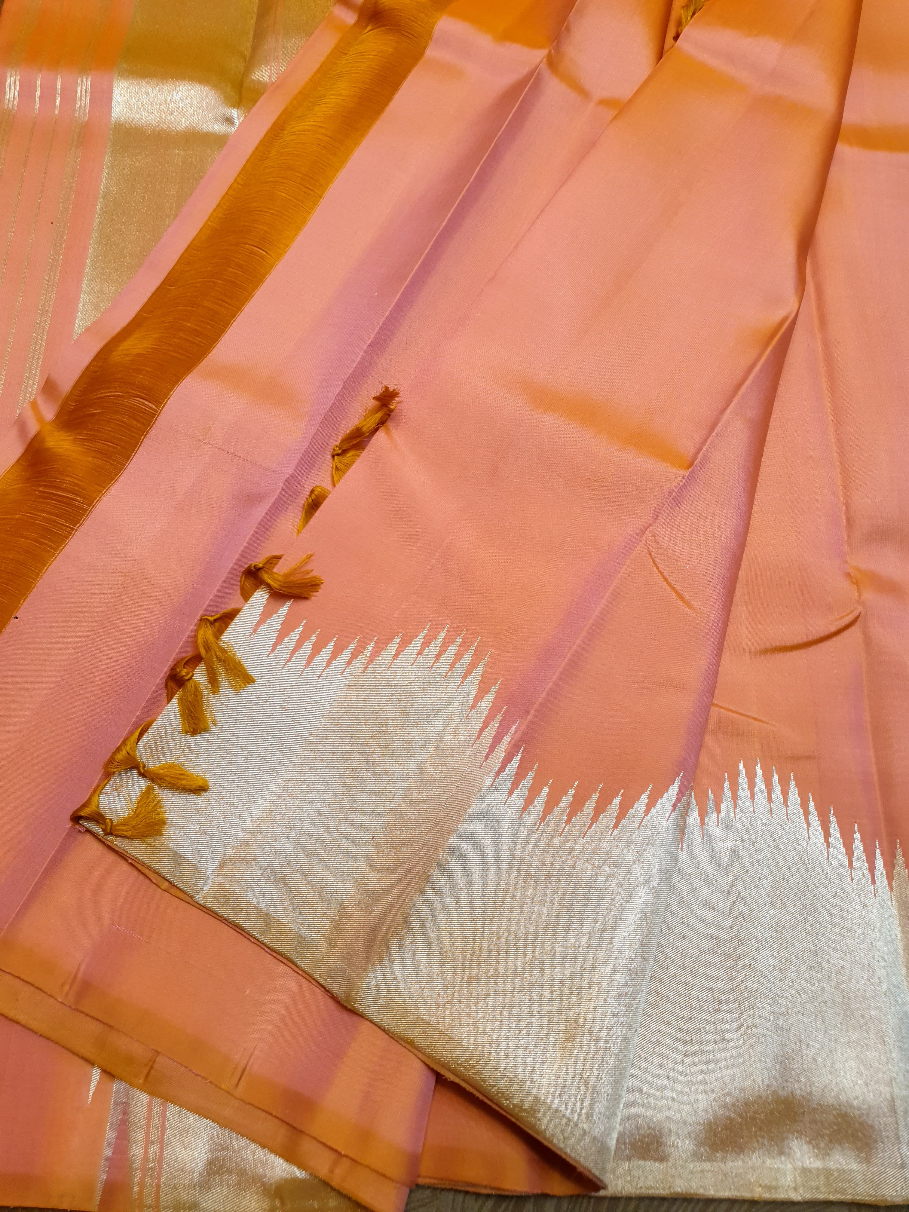 Coral Kanchipuram handloom silk saree featuring a detailed silver zari temple border and luxurious silver accents.