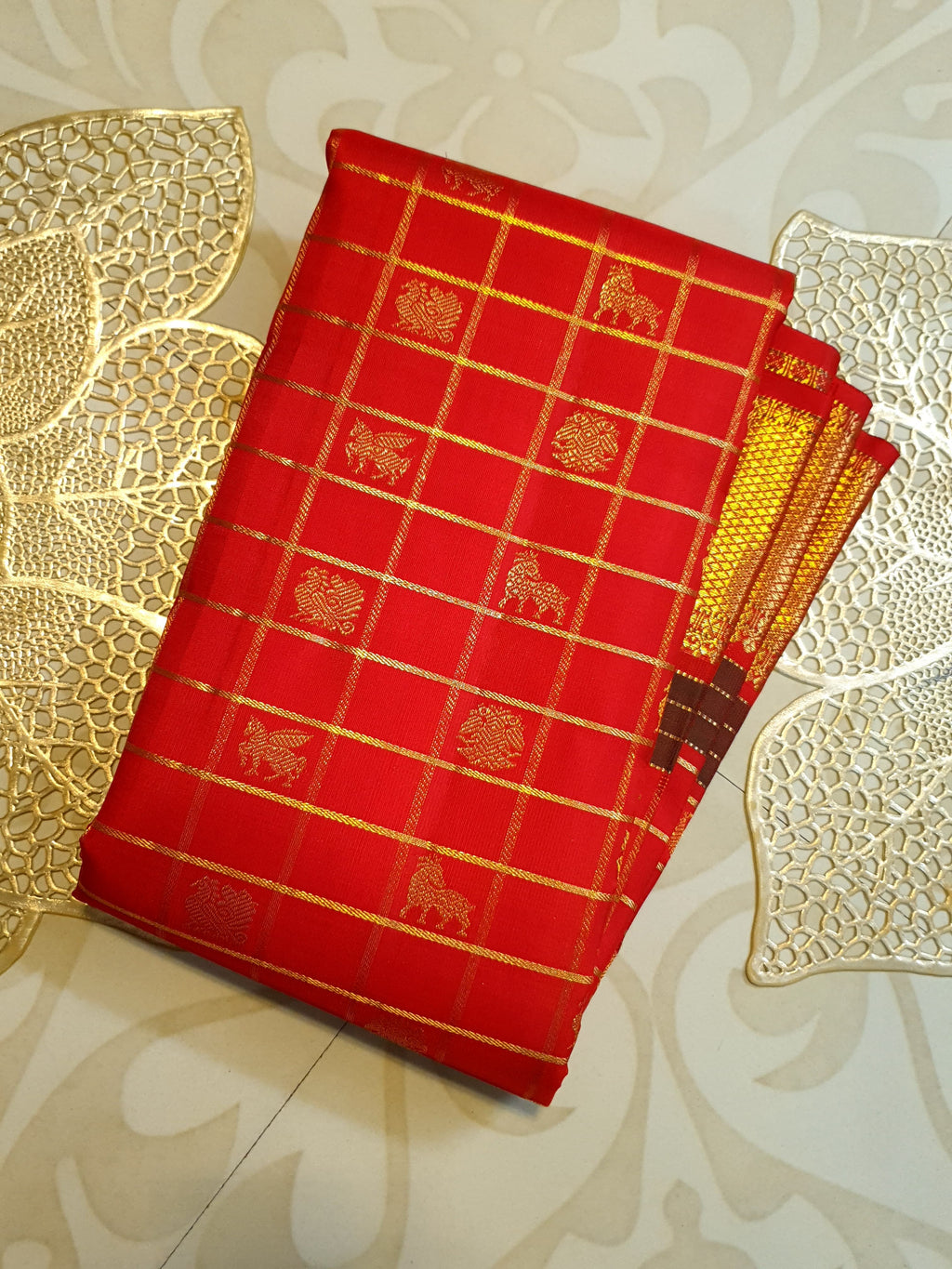 Rustic red Kanchipuram handloom silk saree featuring 3G pure gold zari checks, traditional buttas, and a rich woven border.