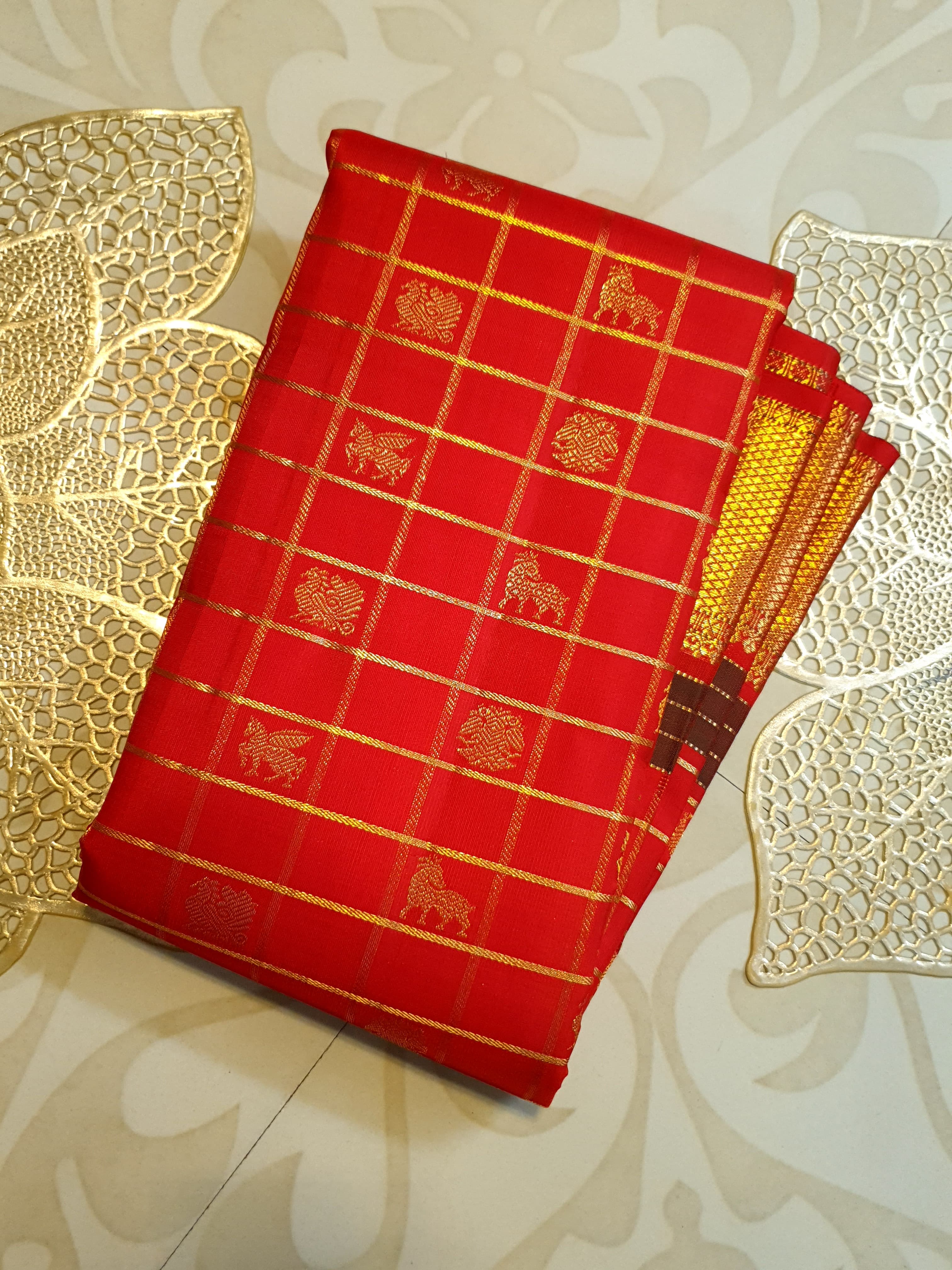 Rustic red Kanchipuram handloom silk saree featuring 3G pure gold zari checks, traditional buttas, and a rich woven border.