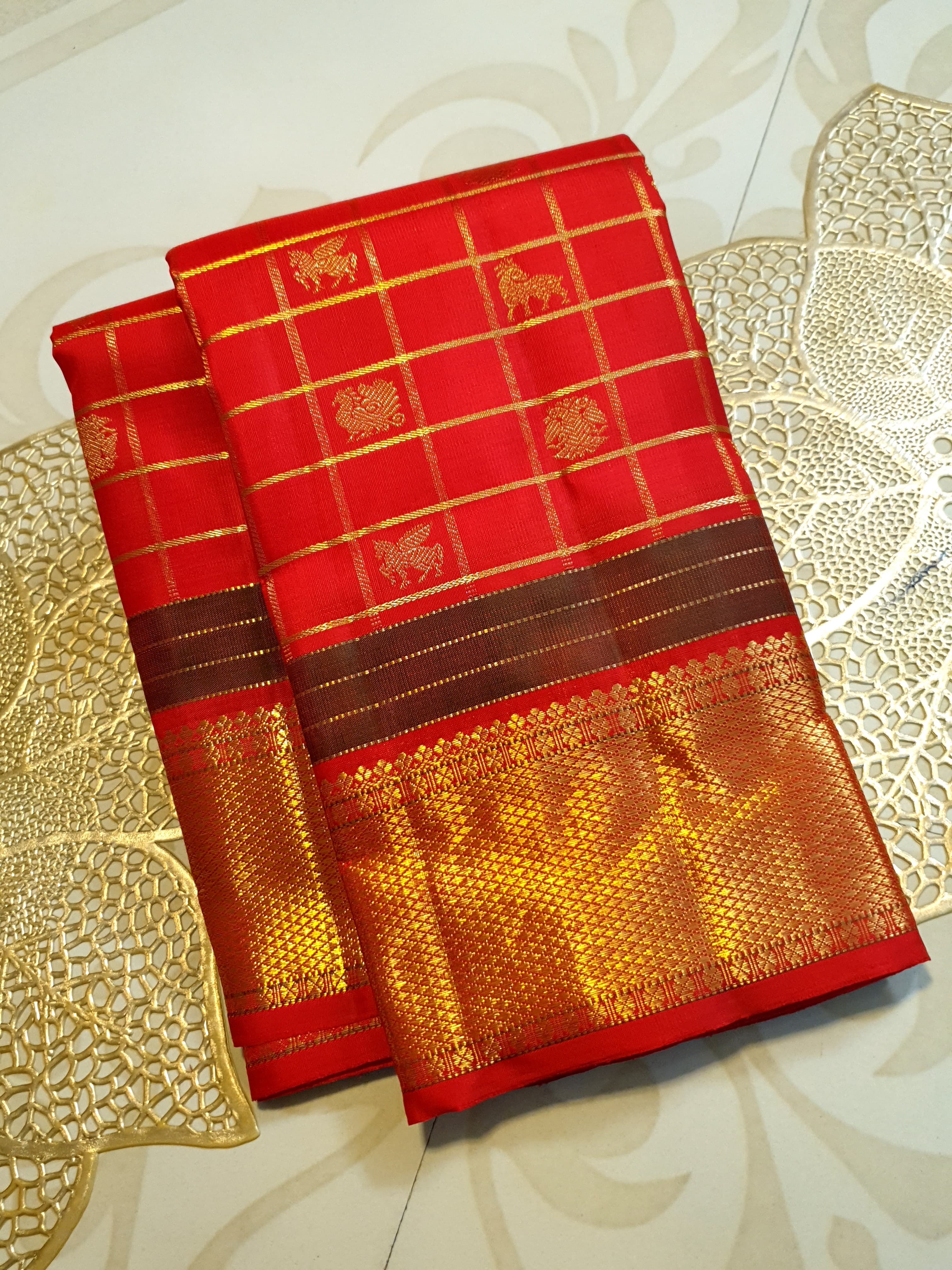 Rustic red Kanchipuram handloom silk saree featuring 3G pure gold zari checks, traditional buttas, and a rich woven border.