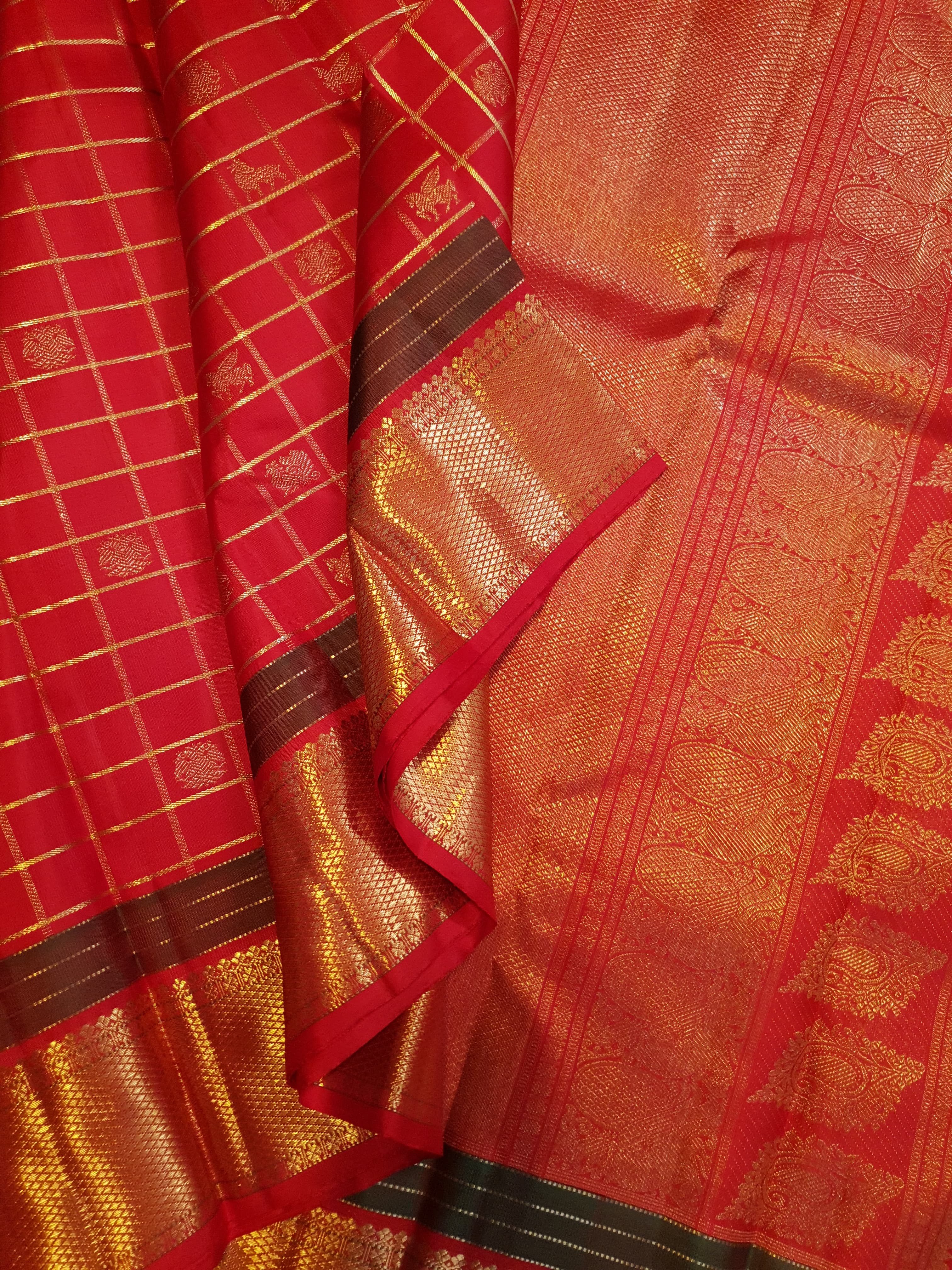Rustic red Kanchipuram handloom silk saree featuring 3G pure gold zari checks, traditional buttas, and a rich woven border.