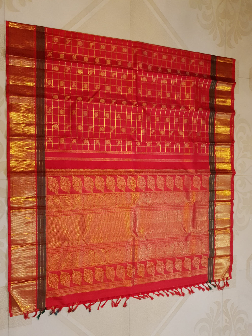 Rustic red Kanchipuram handloom silk saree featuring 3G pure gold zari checks, traditional buttas, and a rich woven border.