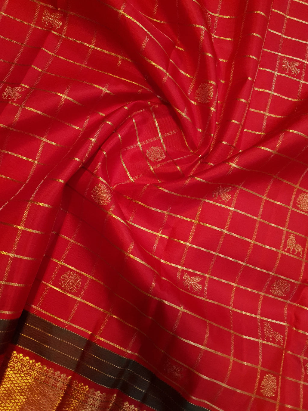 Rustic red Kanchipuram handloom silk saree featuring 3G pure gold zari checks, traditional buttas, and a rich woven border.