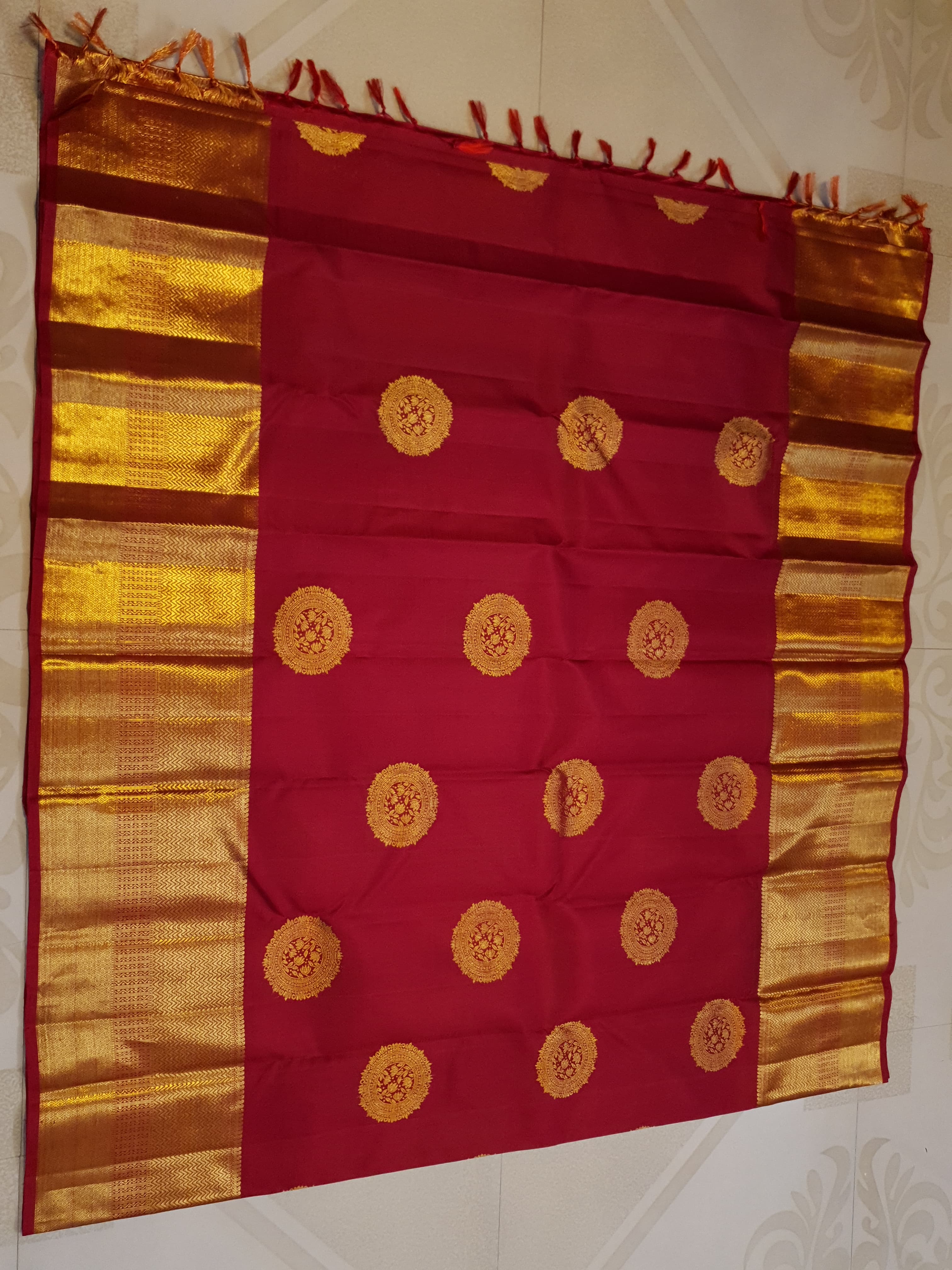 Rustic red Kanchipuram handloom pattu silk saree featuring intricate 2G gold roundel motifs, classic gold zari borders, and a certified silk mark weave.