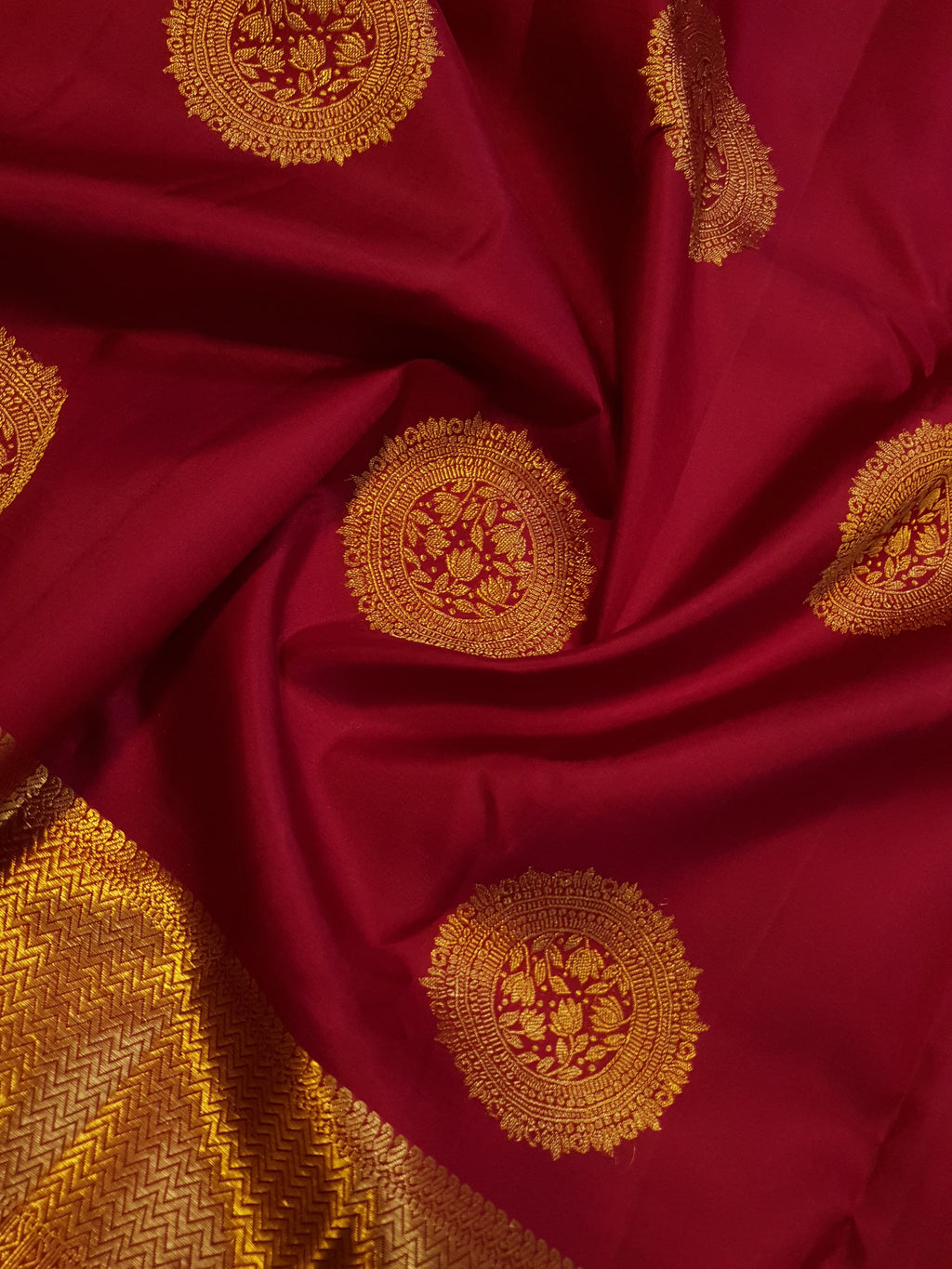 Rustic red Kanchipuram handloom pattu silk saree featuring intricate 2G gold roundel motifs, classic gold zari borders, and a certified silk mark weave.