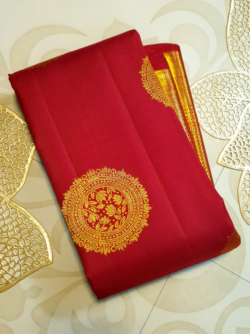 Rustic red Kanchipuram handloom pattu silk saree featuring intricate 2G gold roundel motifs, classic gold zari borders, and a certified silk mark weave.
