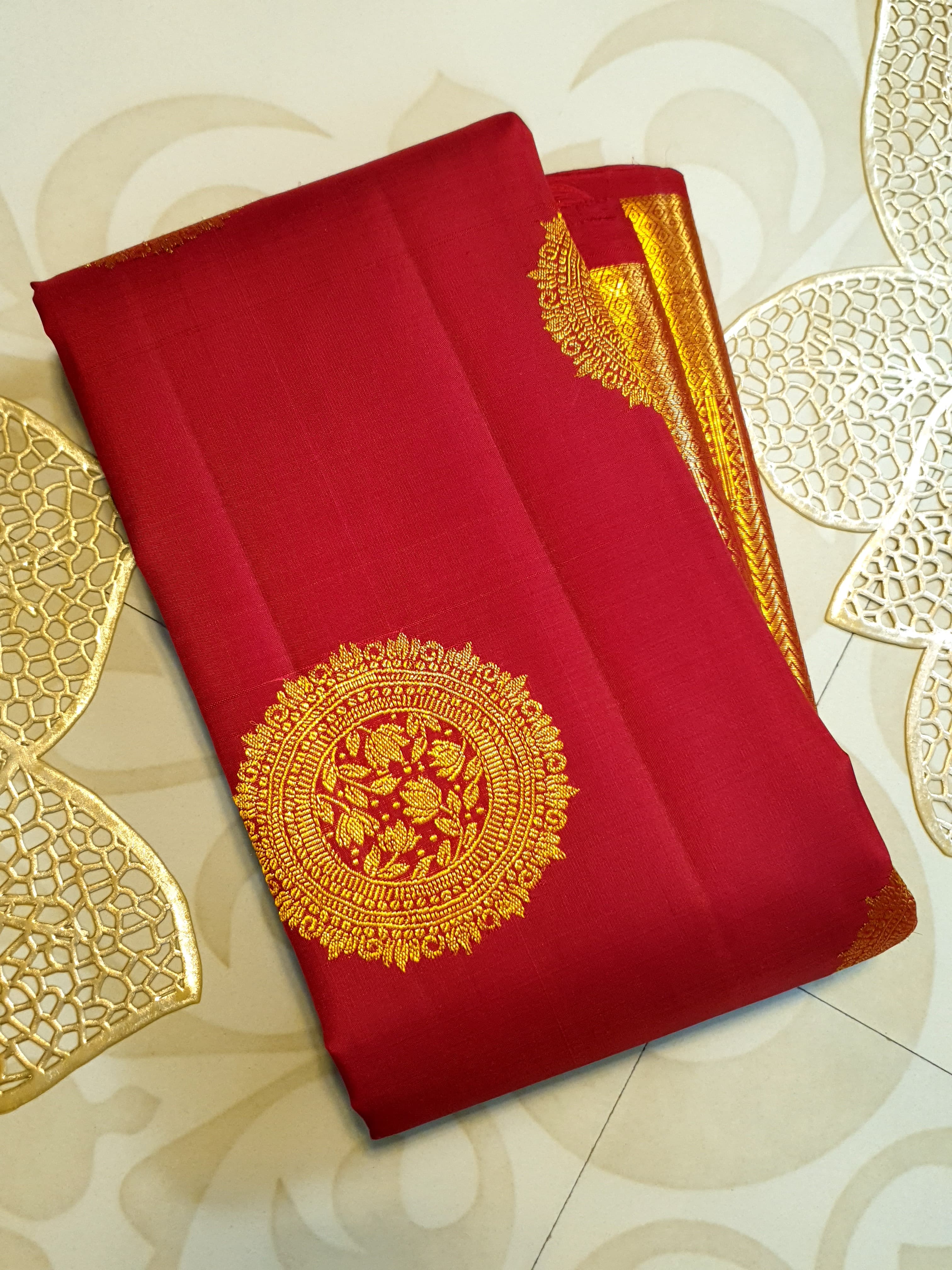 Rustic red Kanchipuram handloom pattu silk saree featuring intricate 2G gold roundel motifs, classic gold zari borders, and a certified silk mark weave.