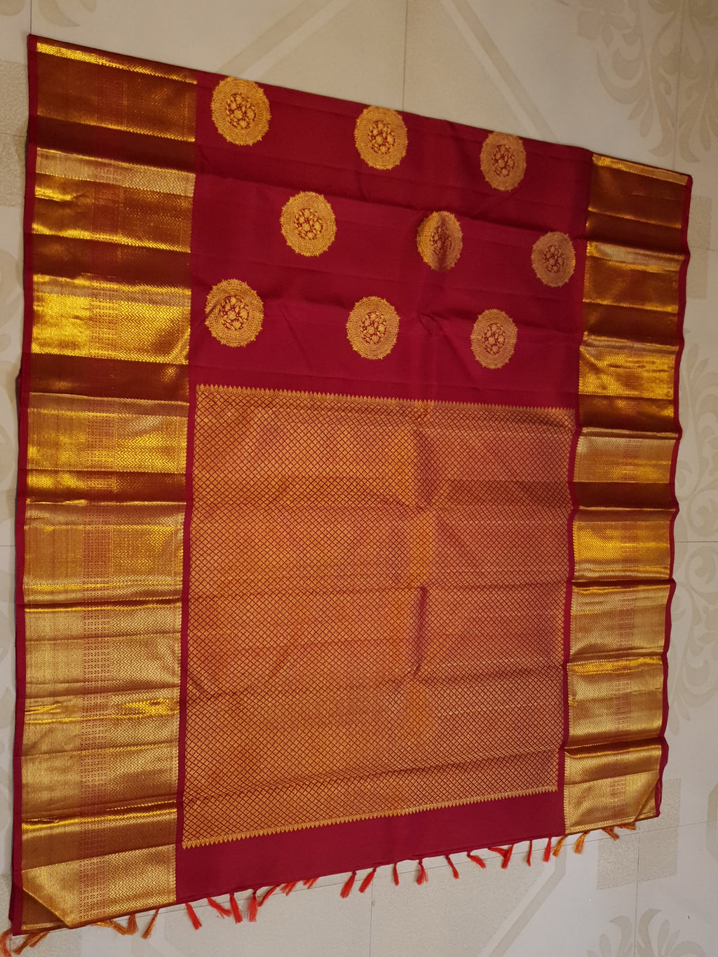 Rustic red Kanchipuram handloom pattu silk saree featuring intricate 2G gold roundel motifs, classic gold zari borders, and a certified silk mark weave.
