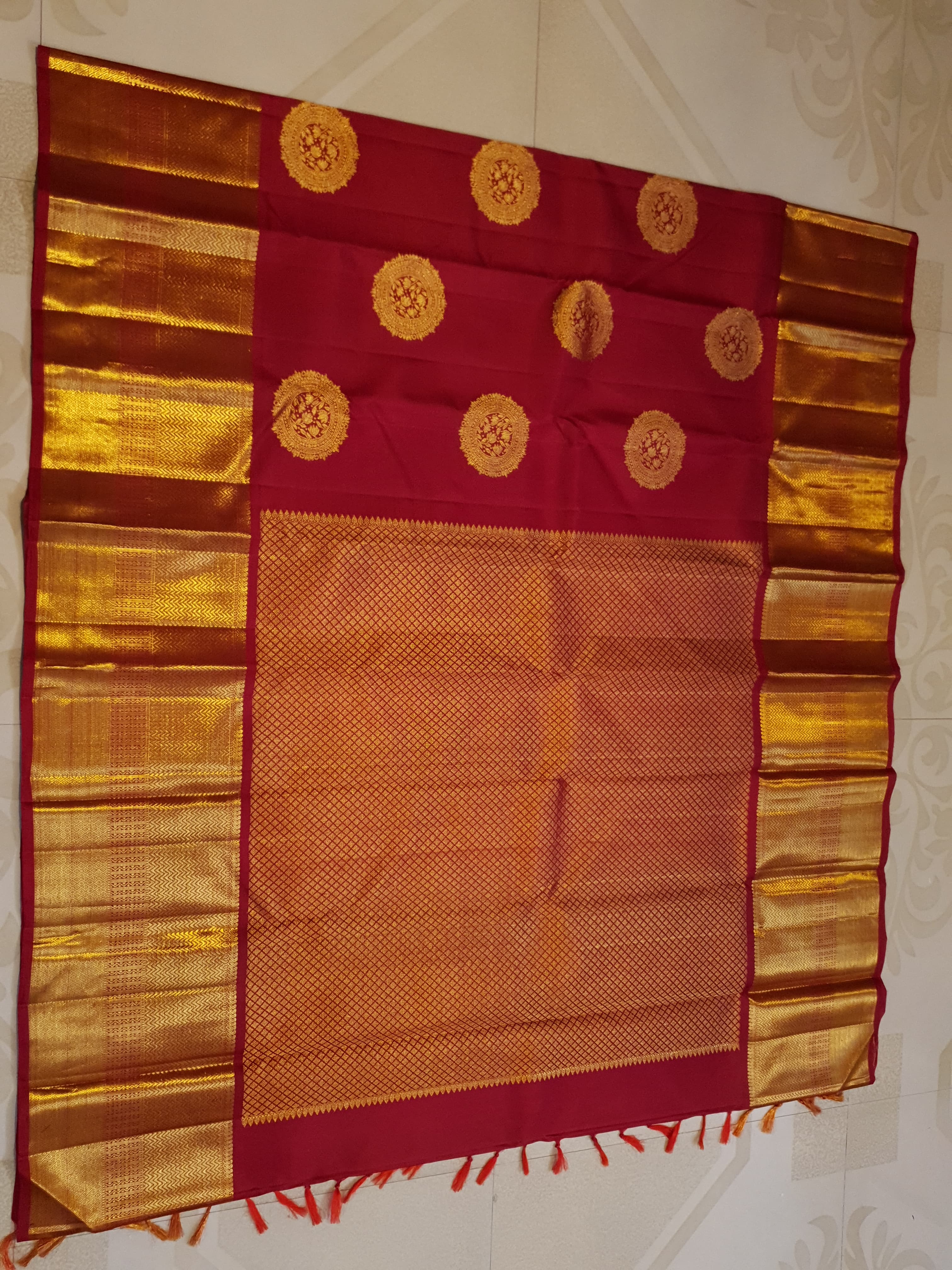 Rustic red Kanchipuram handloom pattu silk saree featuring intricate 2G gold roundel motifs, classic gold zari borders, and a certified silk mark weave.