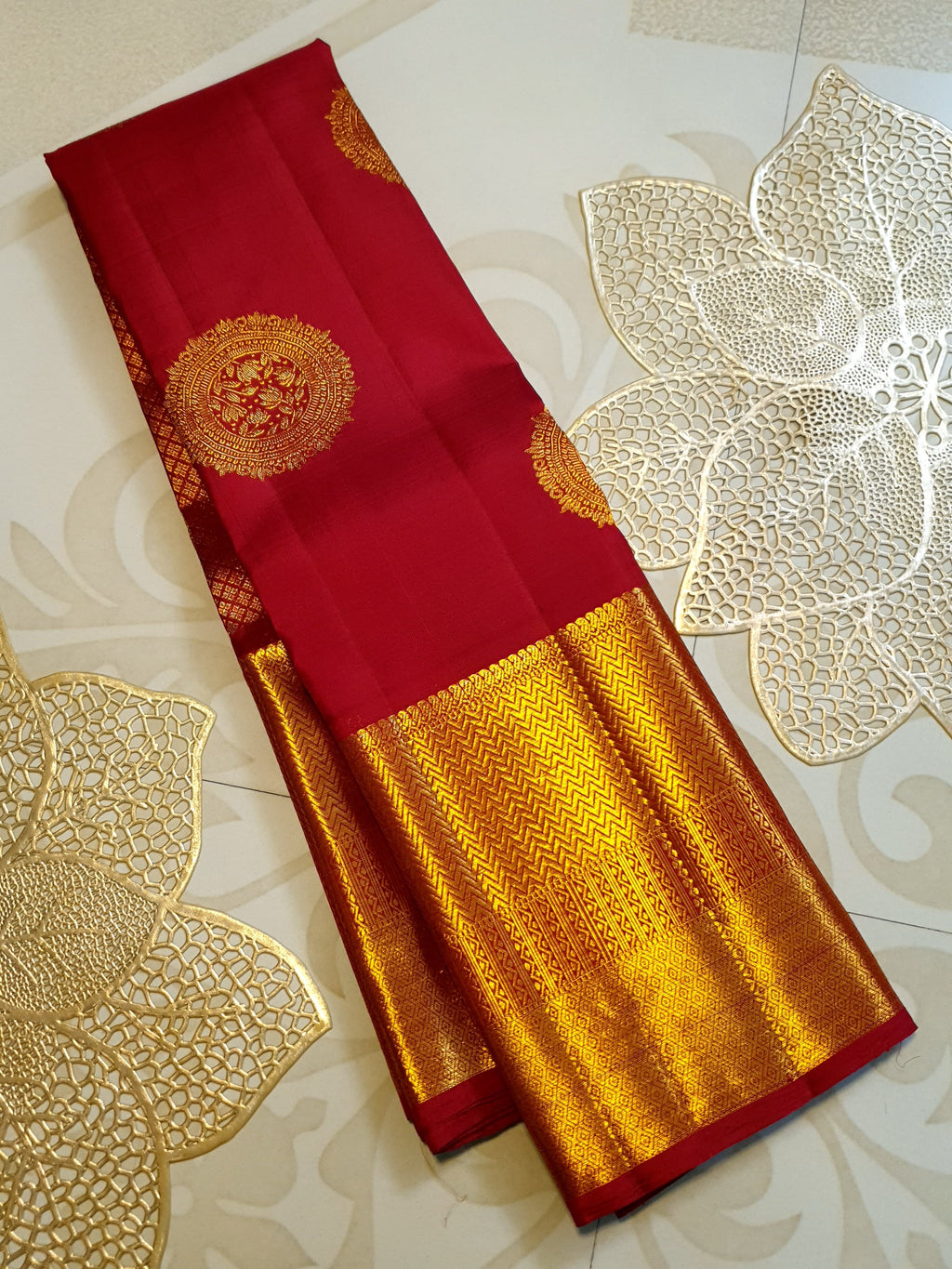 Rustic red Kanchipuram handloom pattu silk saree featuring intricate 2G gold roundel motifs, classic gold zari borders, and a certified silk mark weave.