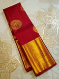 Rustic red Kanchipuram handloom pattu silk saree featuring intricate 2G gold roundel motifs, classic gold zari borders, and a certified silk mark weave.