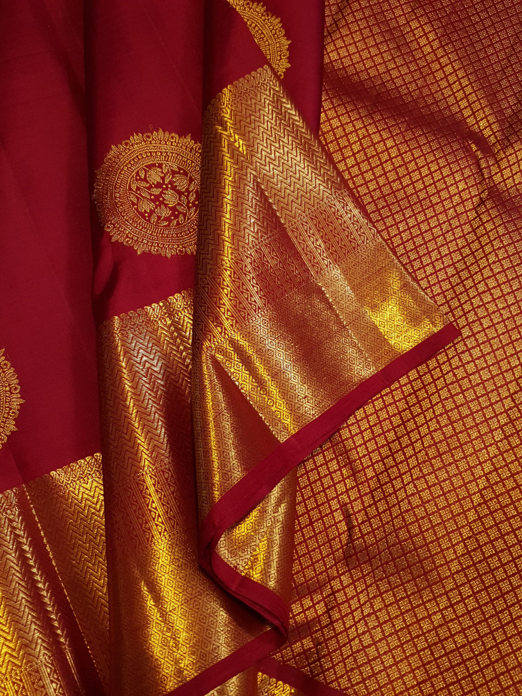Rustic red Kanchipuram handloom pattu silk saree featuring intricate 2G gold roundel motifs, classic gold zari borders, and a certified silk mark weave.