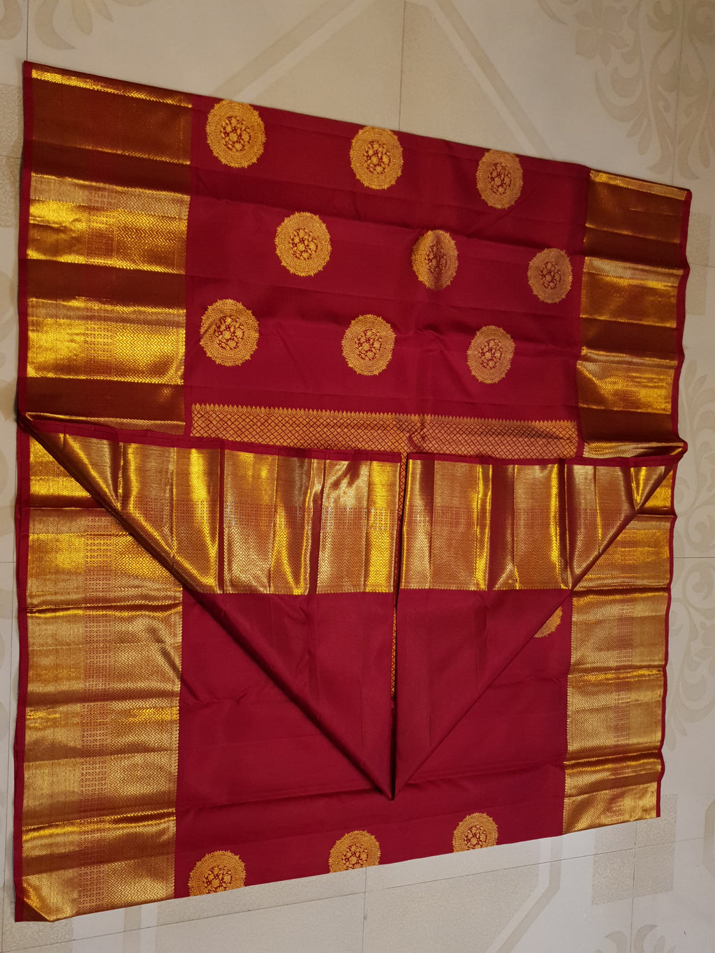 Rustic red Kanchipuram handloom pattu silk saree featuring intricate 2G gold roundel motifs, classic gold zari borders, and a certified silk mark weave.