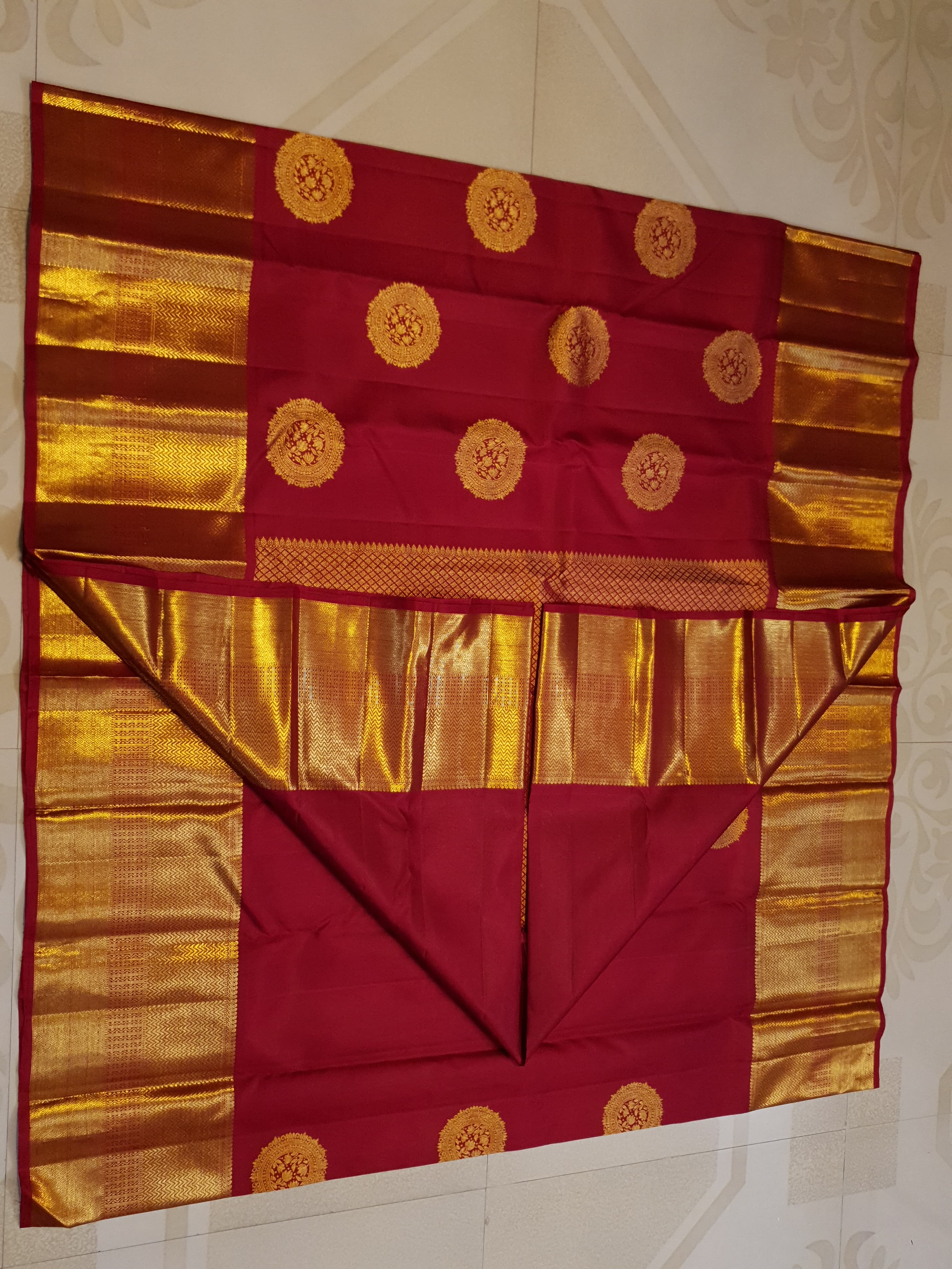 Rustic red Kanchipuram handloom pattu silk saree featuring intricate 2G gold roundel motifs, classic gold zari borders, and a certified silk mark weave.